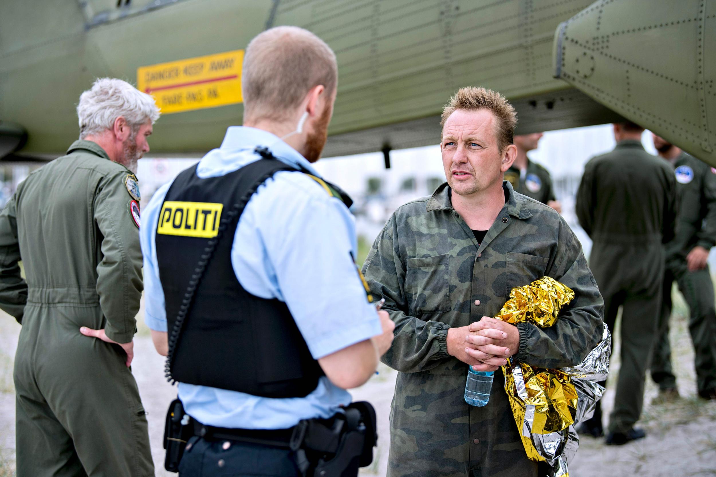 Peter Madsen, right, talks to a police officer after being rescued from his sinking submarine