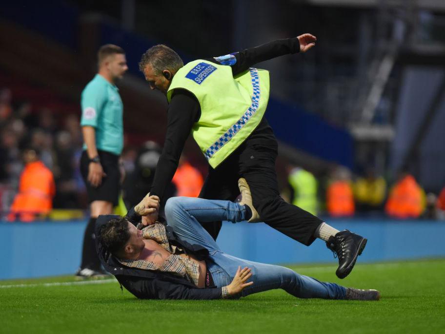 A fan is apprehendedafter invading the pitch at Ewood Park