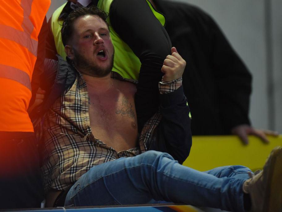 A fan is eventually led away by stewards after running onto Blackburn's pitch