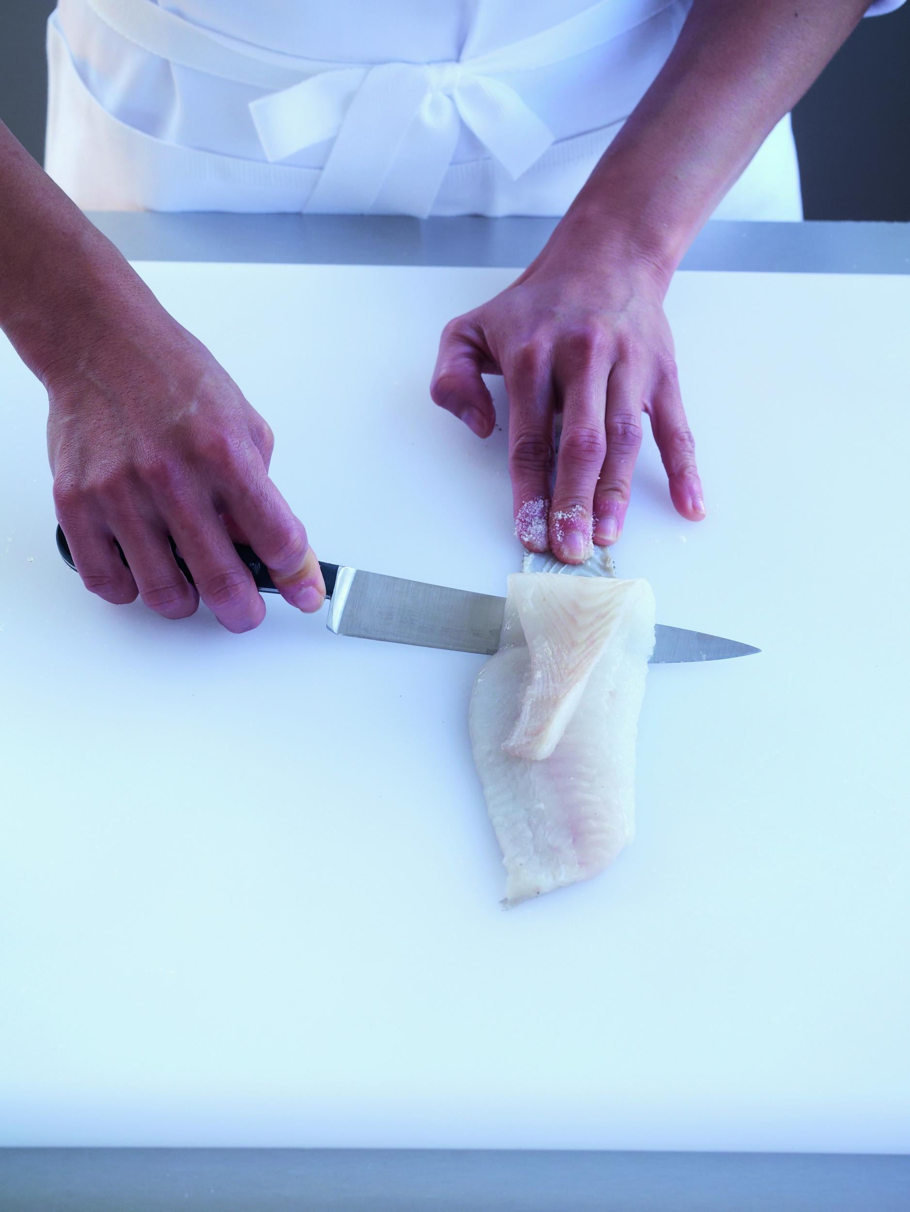 3. Working the fillet away from the skin, using a sawing action, while keeping the knife pressed firmly against the skin