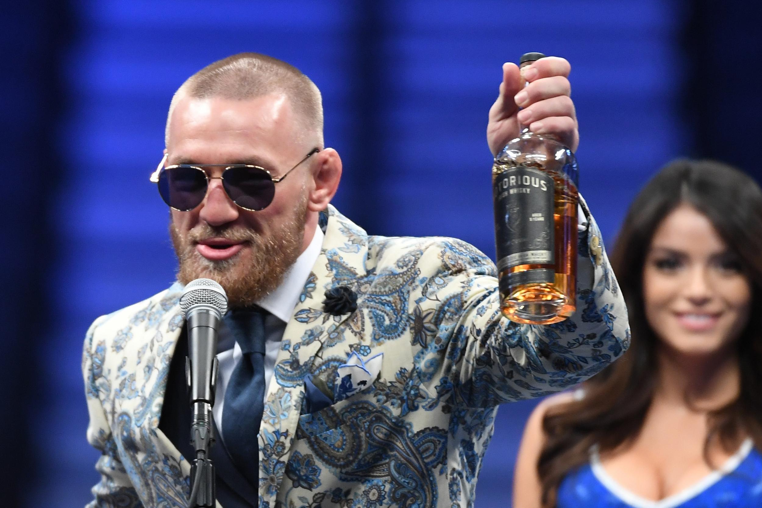 McGregor holds up a bottle of his whiskey