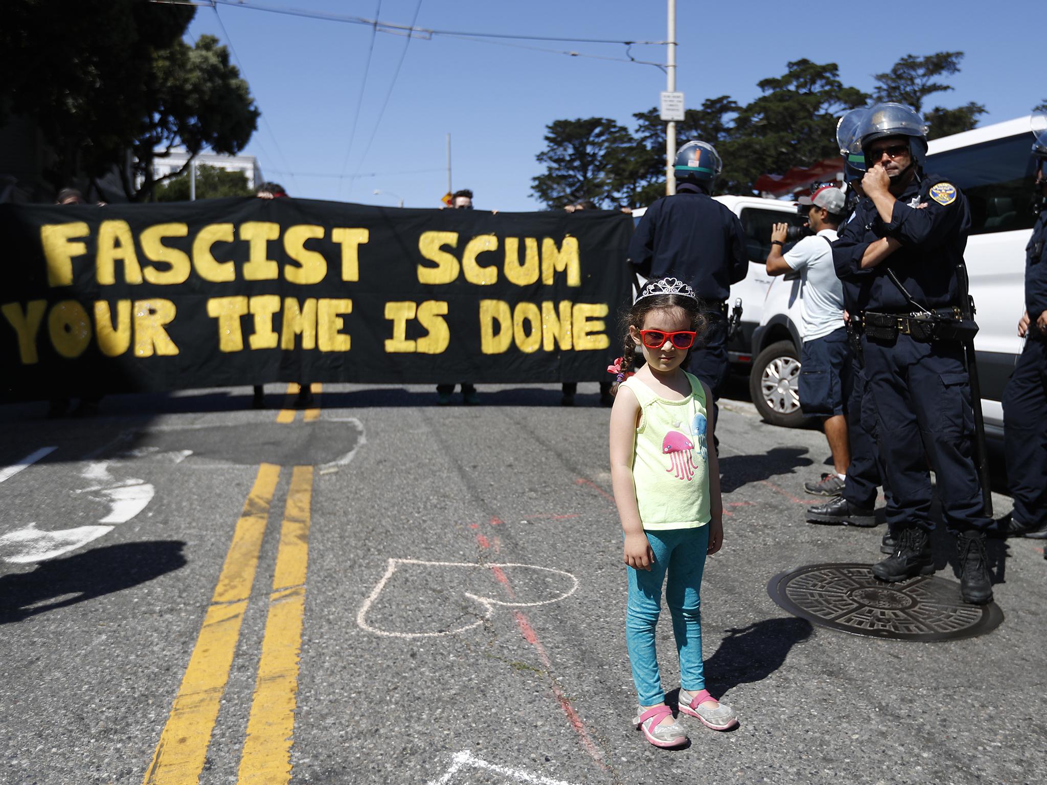 A young girl gets into the party spirit next to a line of police officers by Alamo Square after a rally expected to attract extremists, including the Ku Klux Klan, was called off