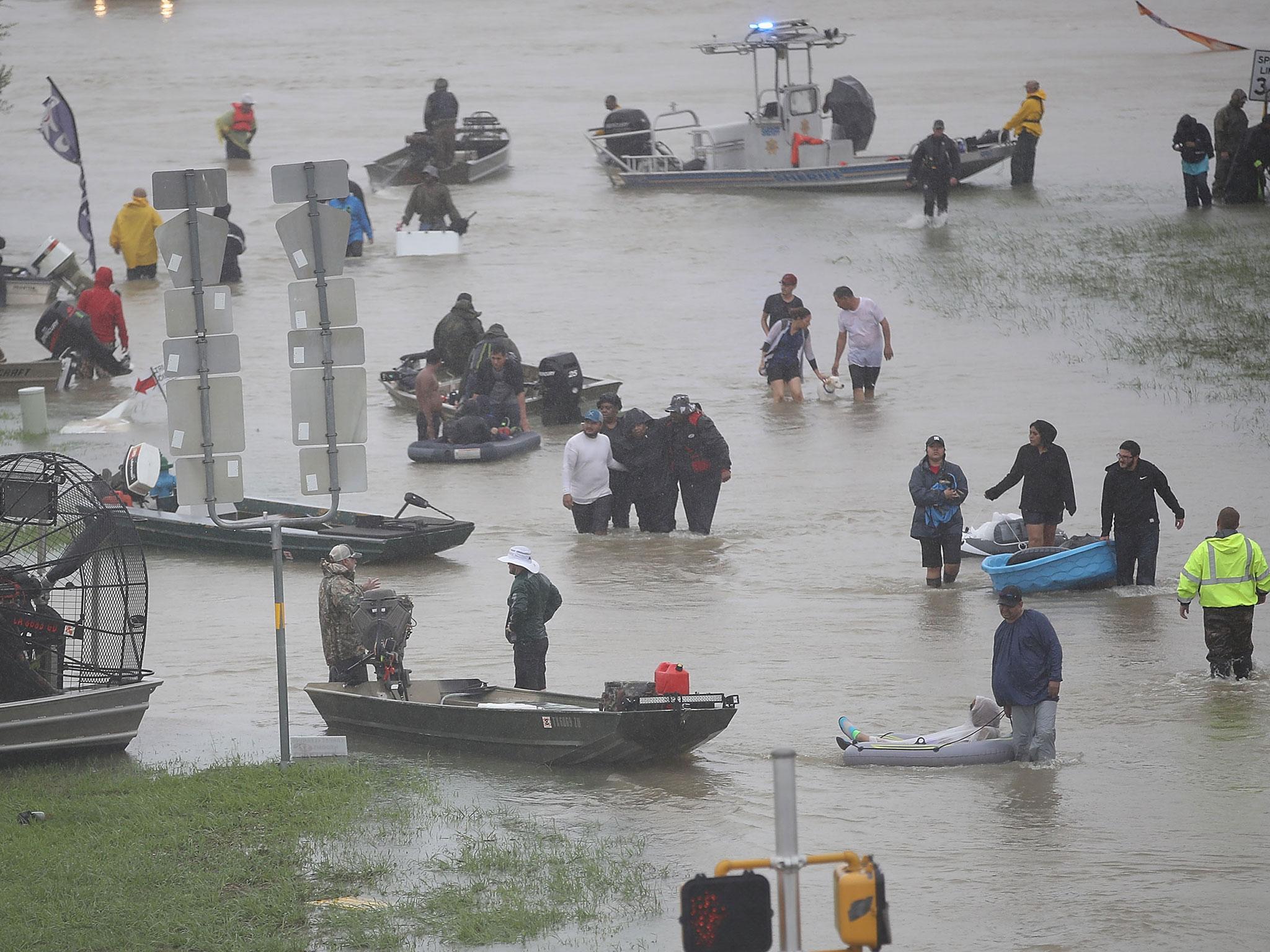 People walk down a flooded street as they evacuate their homes after the area was inundated with flooding from Hurricane Harvey in Houston, Texas