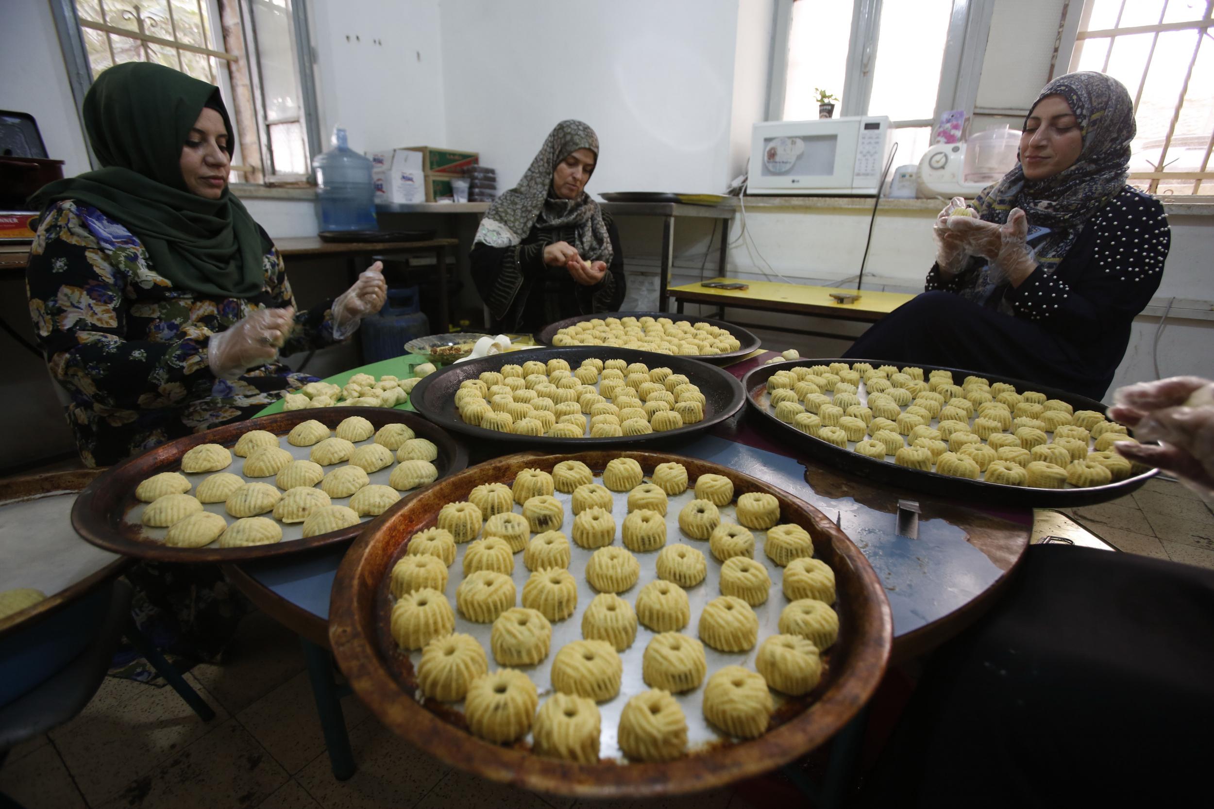 Women in the West Bank town of Hebron make pastries filled with dates or nuts, known as maamoul, on 28 August 2017 in preparation for Eid al-Adha celebrations later this week