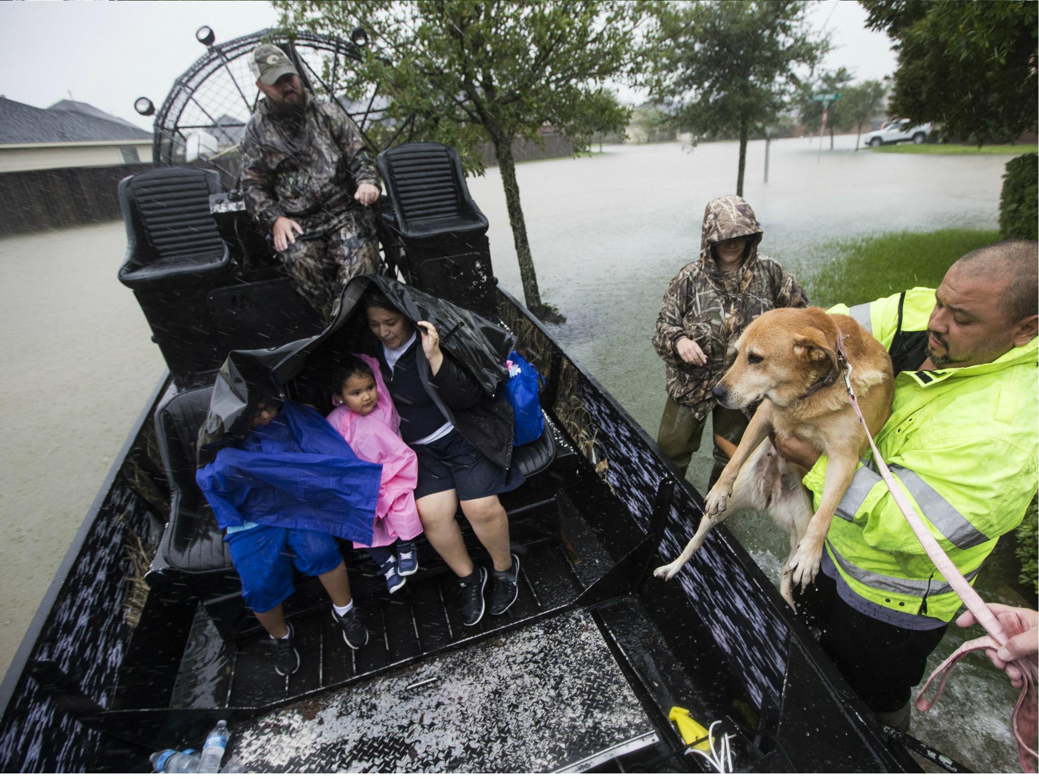 Richard Velasco lifts his dog into an airboat as he and his family are evacuated from their home as water rises from heavy rains in Fort Bend County, Texas