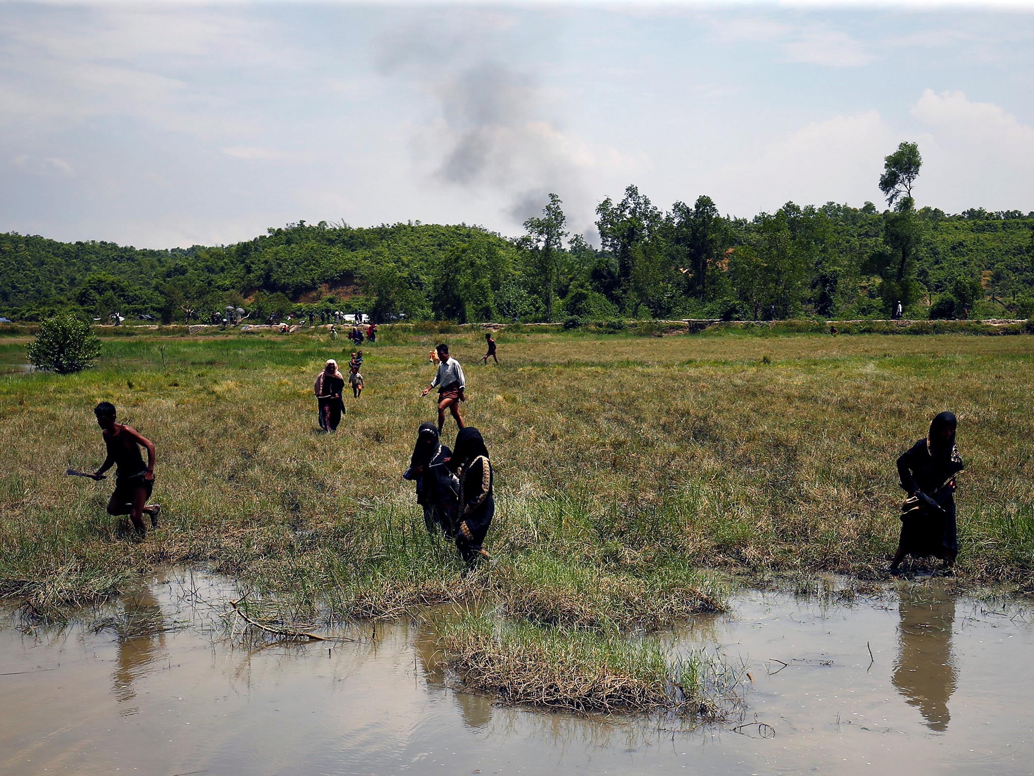 Rohingya people try to come to the Bangladesh side from No Man's Land as smoke rises after a gunshot was heard on the Myanmar side, in Cox's Bazar, Bangladesh