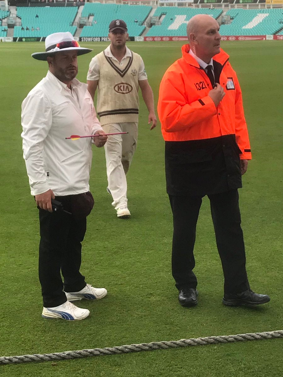 An umpire shows the arrow as a steward and Surrey's Stuart Meaker look on