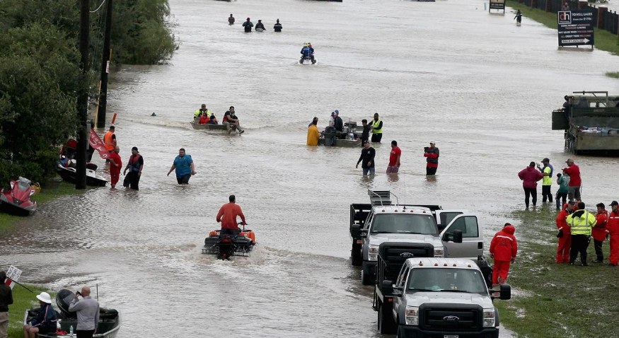 People make their way out of a flooded neighborhood after it was inundated with rain water following Hurricane Harvey