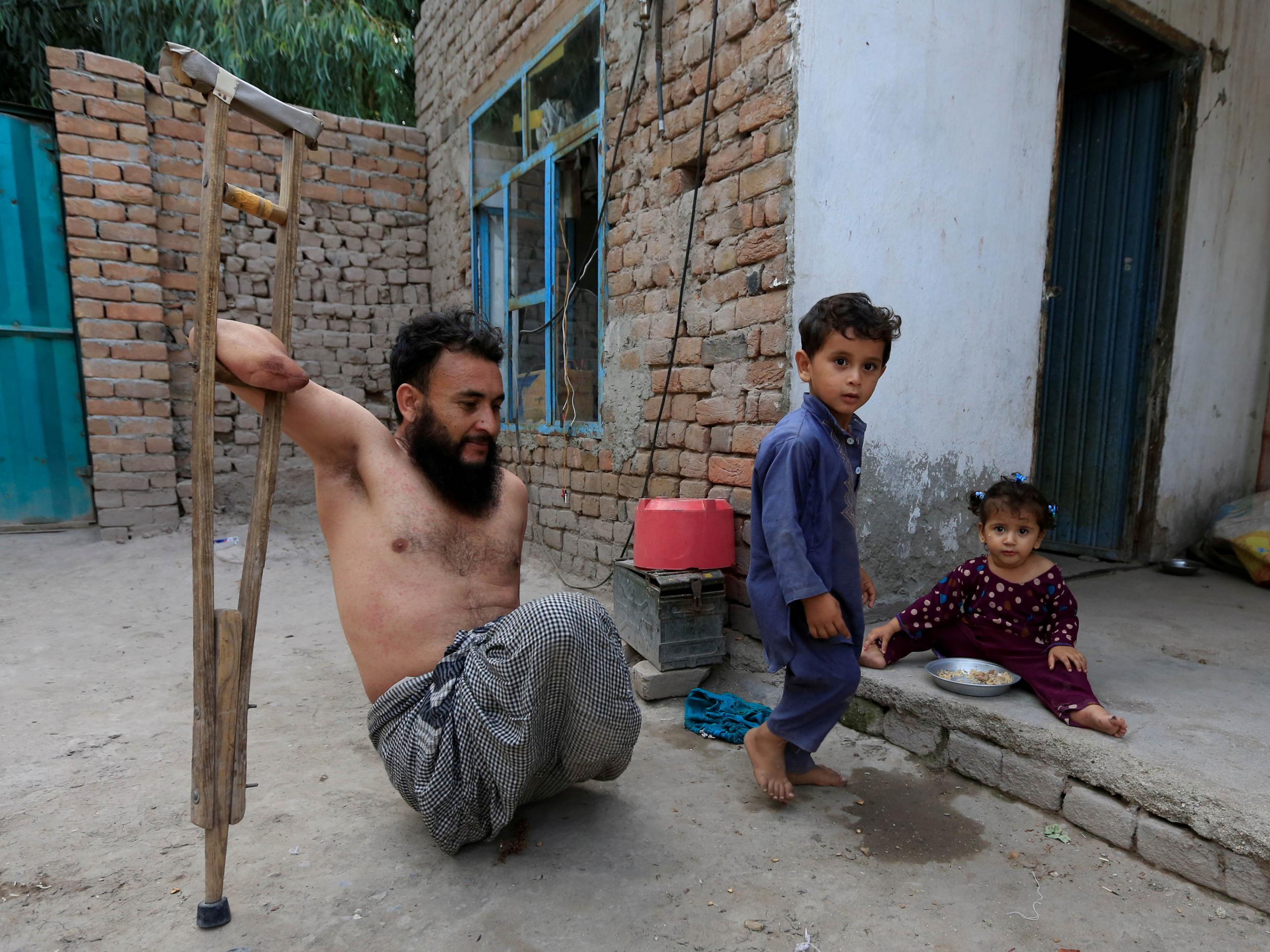 Khushhal Khan Ayobi, 34, a disabled Afghan National Armysoldier, walks with his children at his house in Jalalabad province