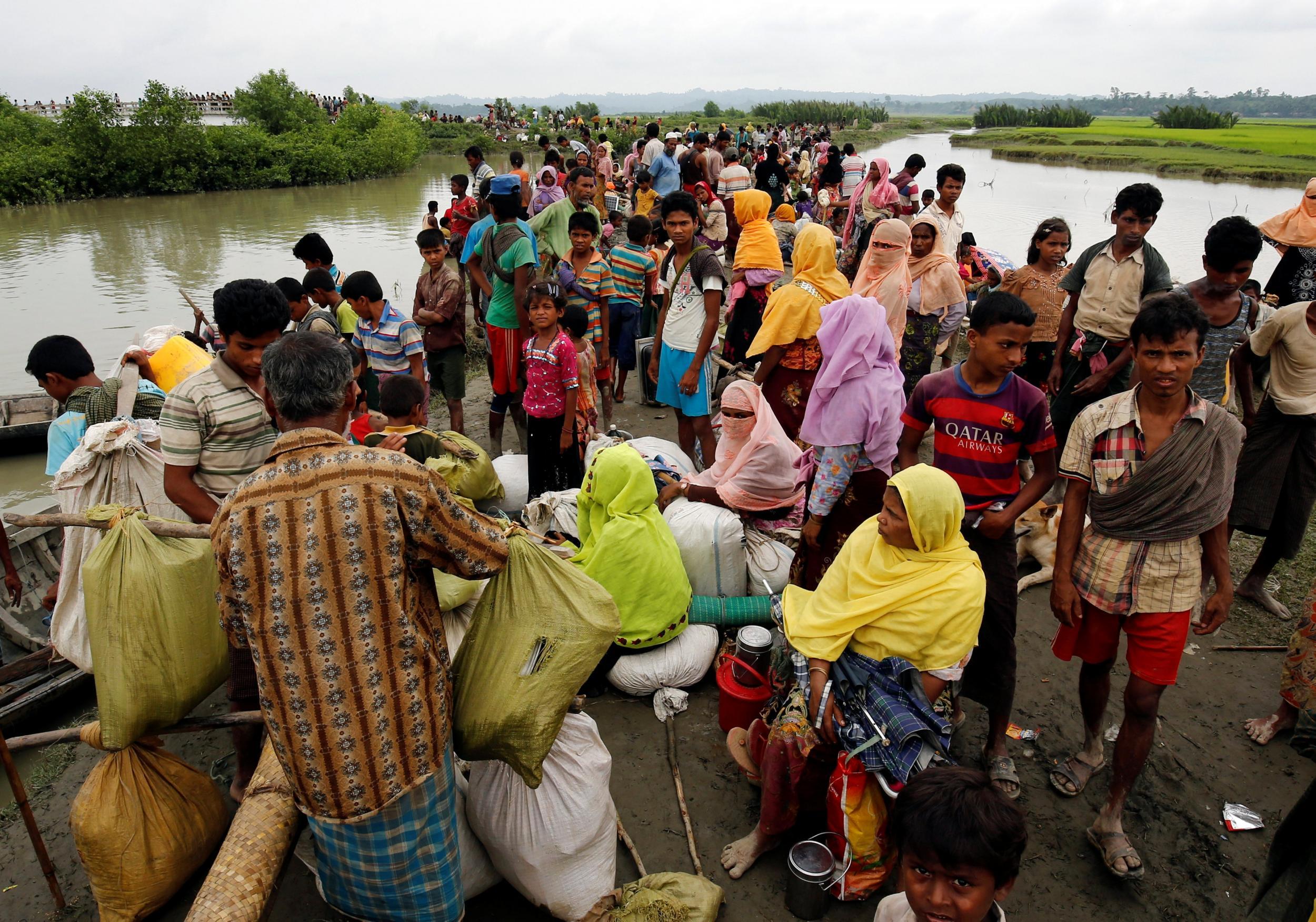 Rohingya refugees are seen waiting for a boat to cross the border through the Naf river in Maungdaw, Burma