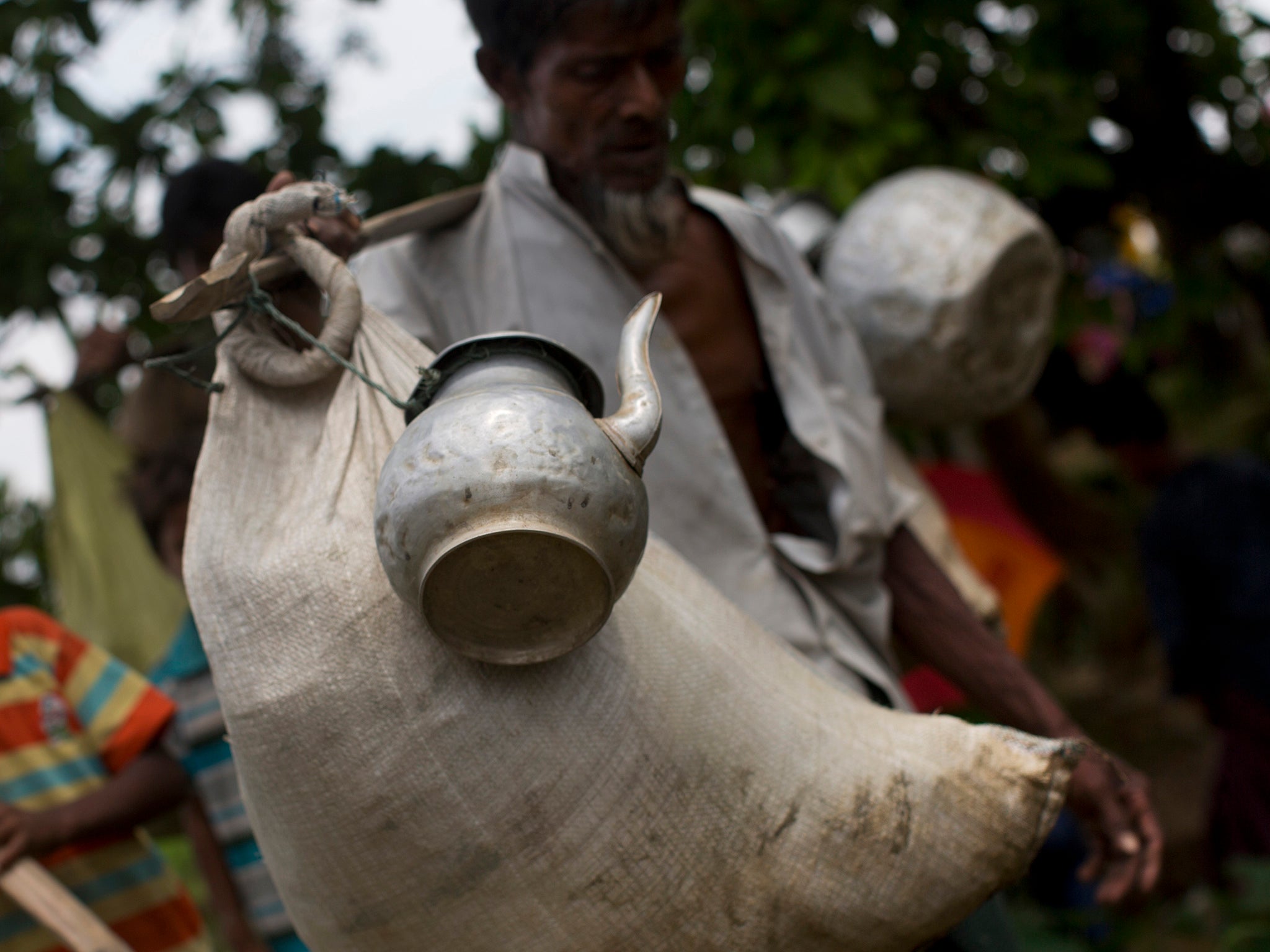 A Rohingya Muslim man arrives with a sack of belongings and a kettle tied to a stick