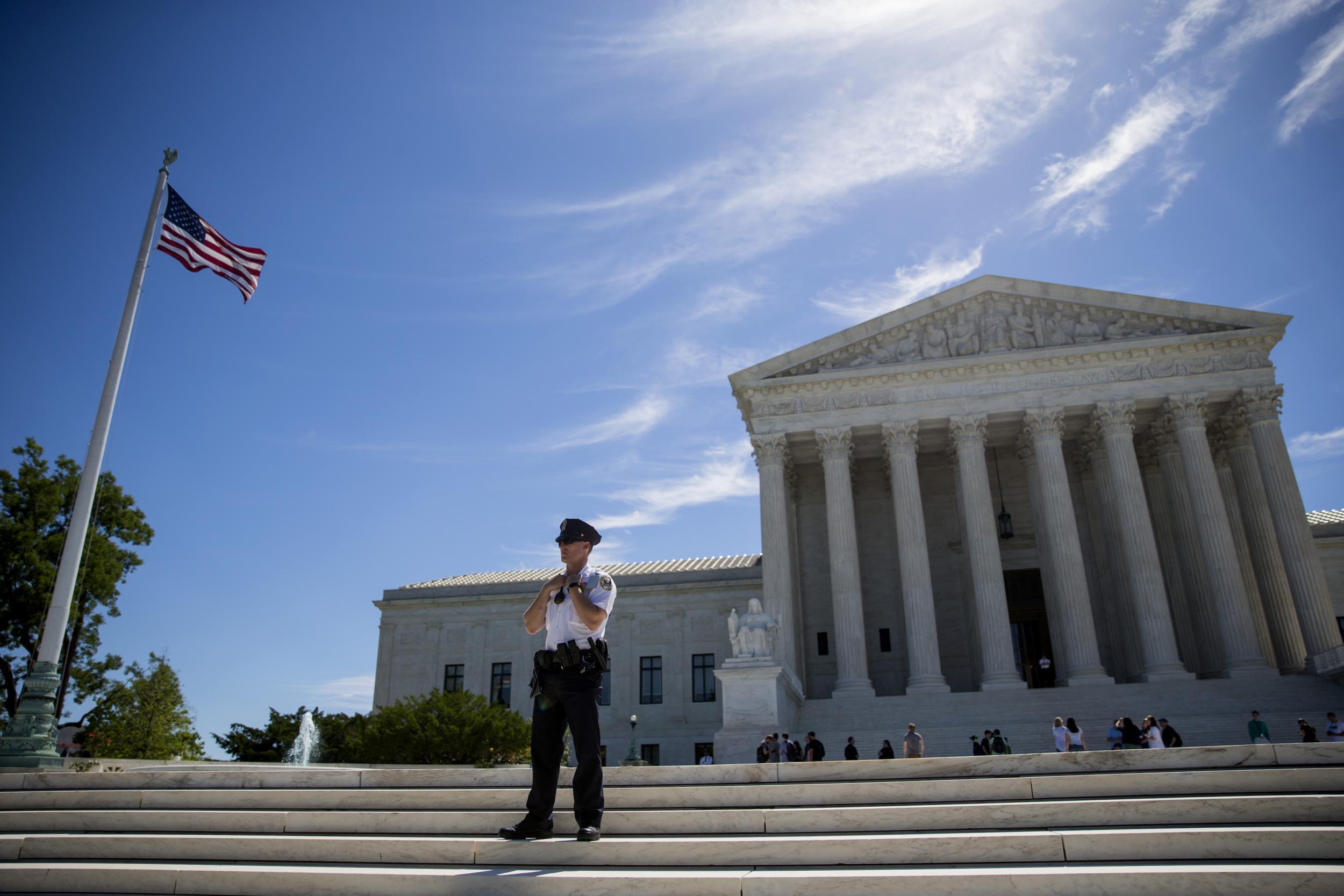 A police officer is seen outside the US Supreme Court after it was announced that the court will allow a limited version of President Donald Trump's travel ban to take effect