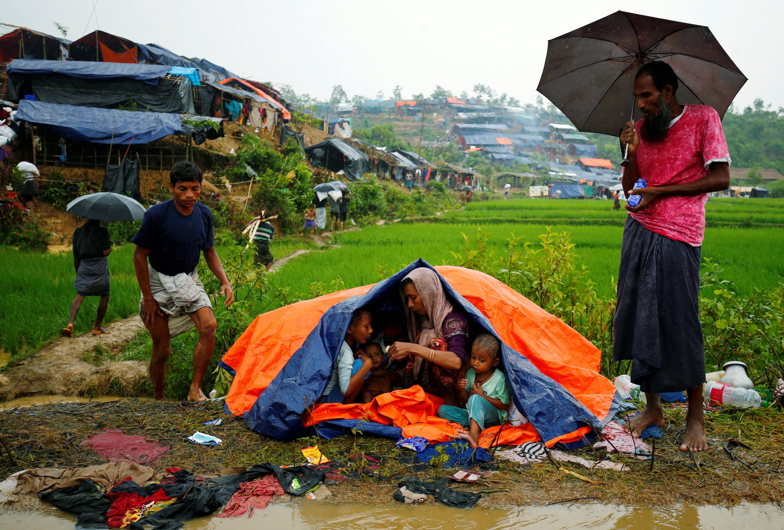 Rohingya refugees sit on the roadside as they take shelter during rain in Cox's Bazar, Bangladesh (Reuters)