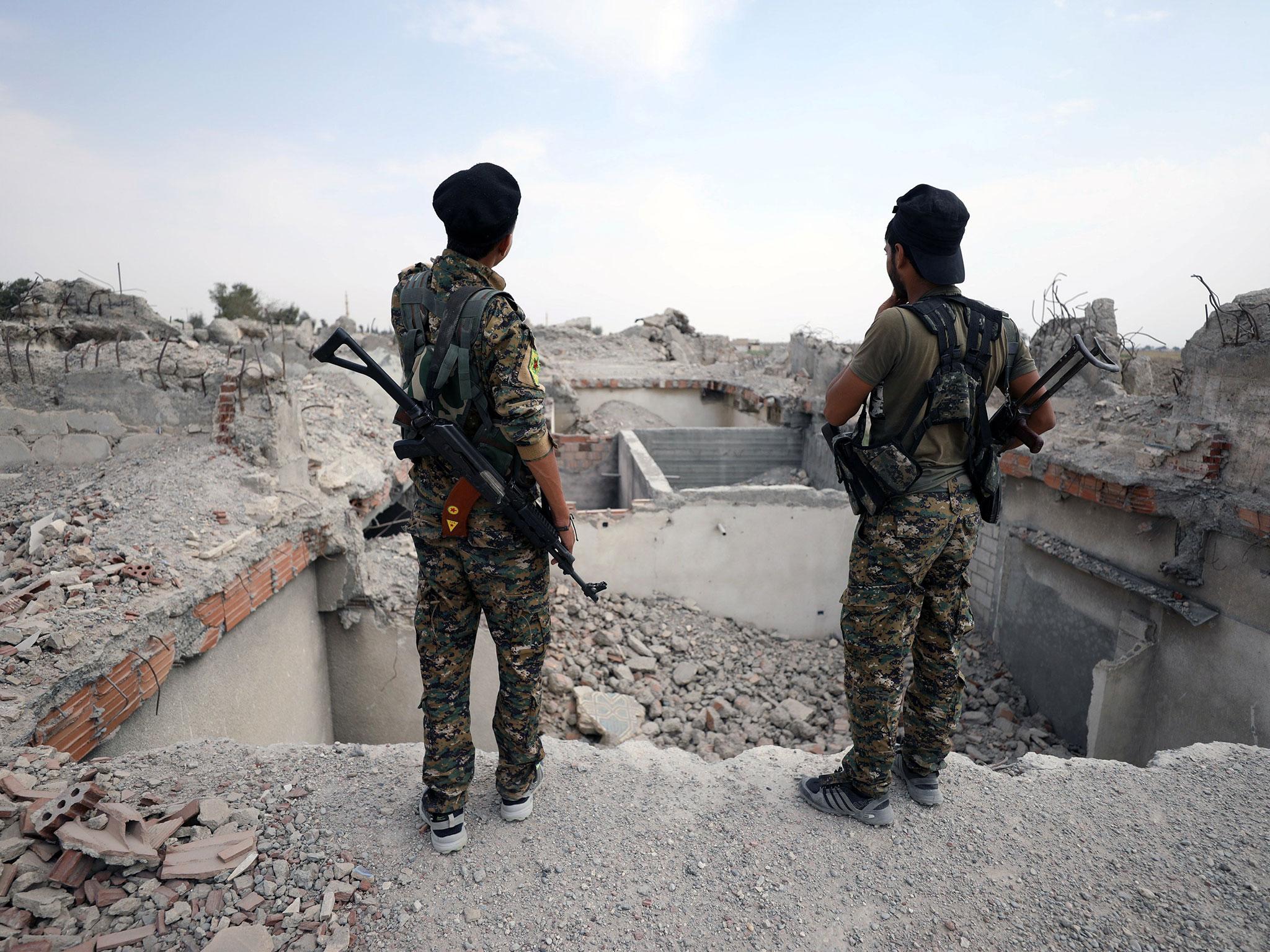 Fighters from the Syrian Democratic Forces (SDF) stand near the destroyed Uwais al-Qarni shrine in Raqqa