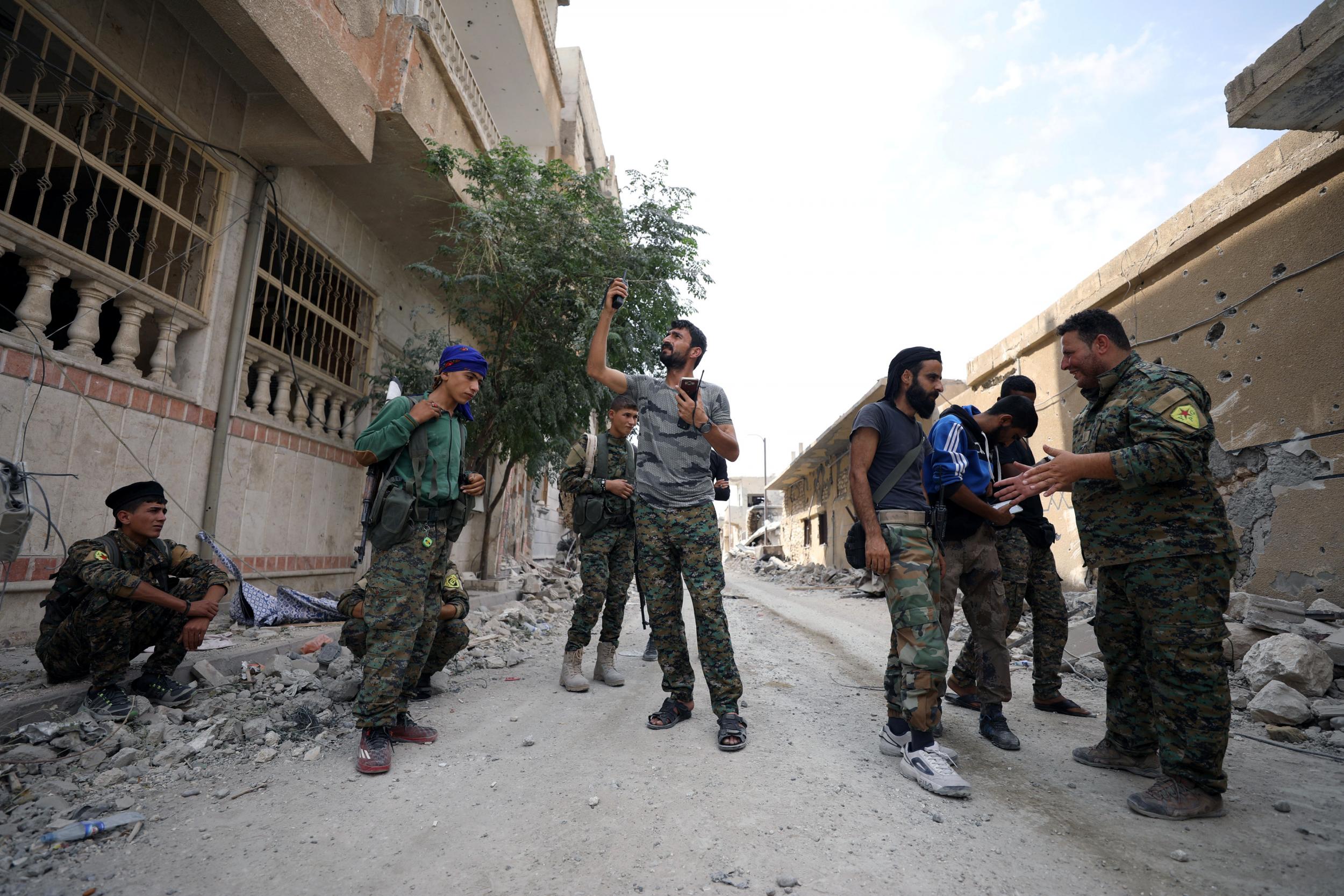 A fighter from the SDF tries to communicate on a radio amid the rubble of a damaged street in Raqqa this month Reuters