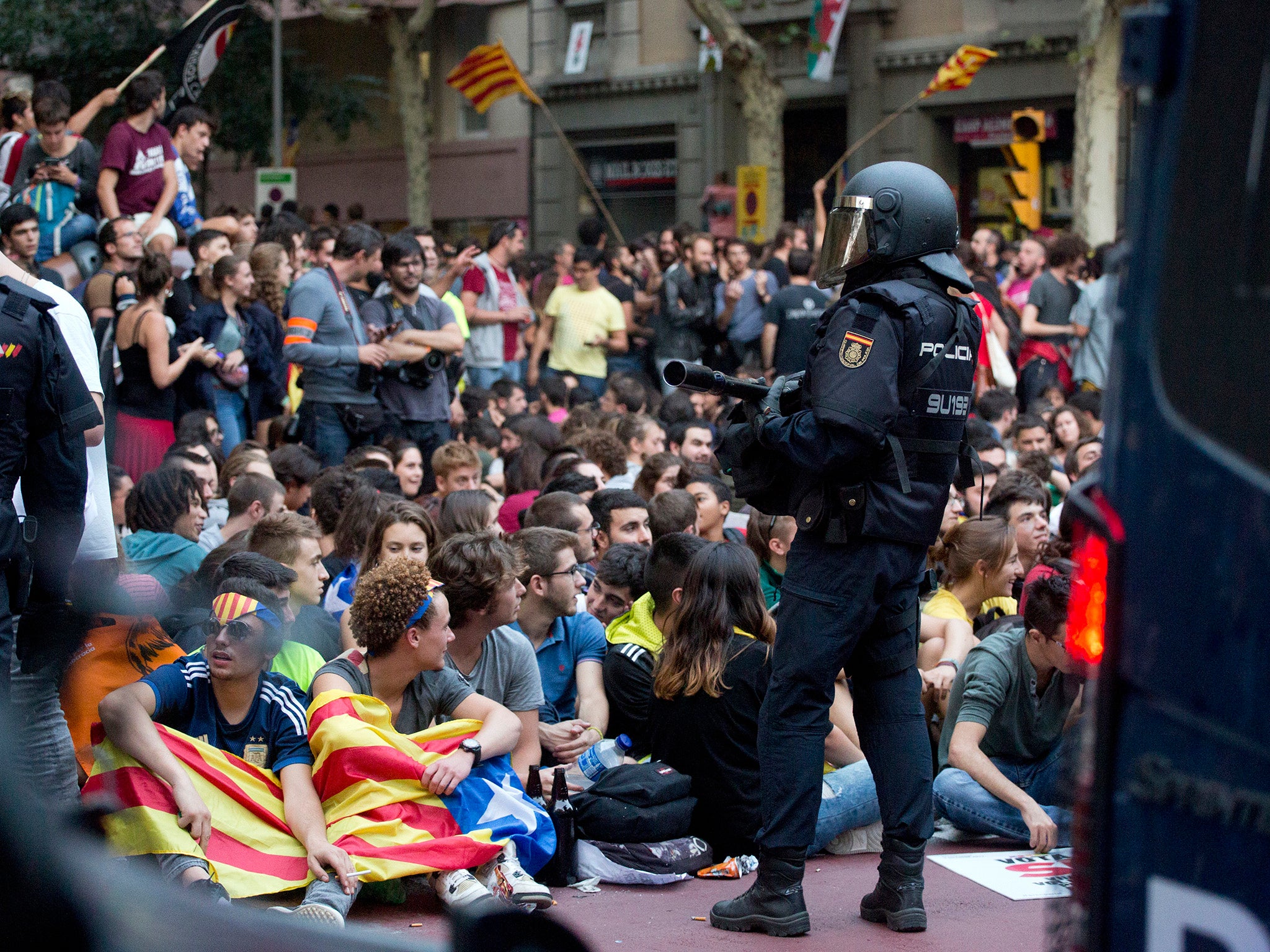 A Spanish nacional police officer stands guard as demonstrators protest outside the main offices of the left wing CUP party in Barcelona