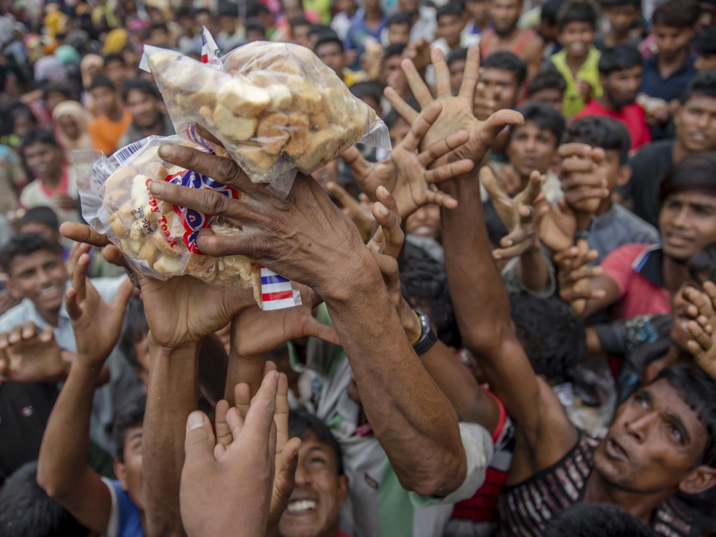 Rohingya Muslims stretch their arms out to receive packets of biscuits thrown at them as handouts