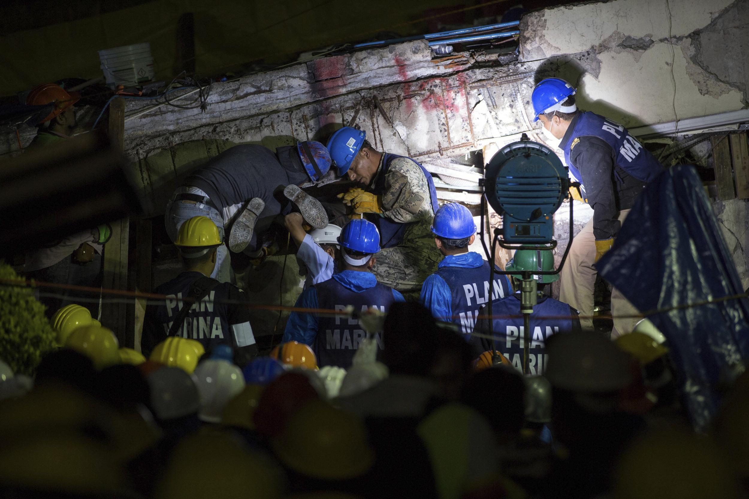 Search and rescue team members work to bring down a large piece of concrete during rescue efforts at the Enrique Rebsamen school in Mexico City