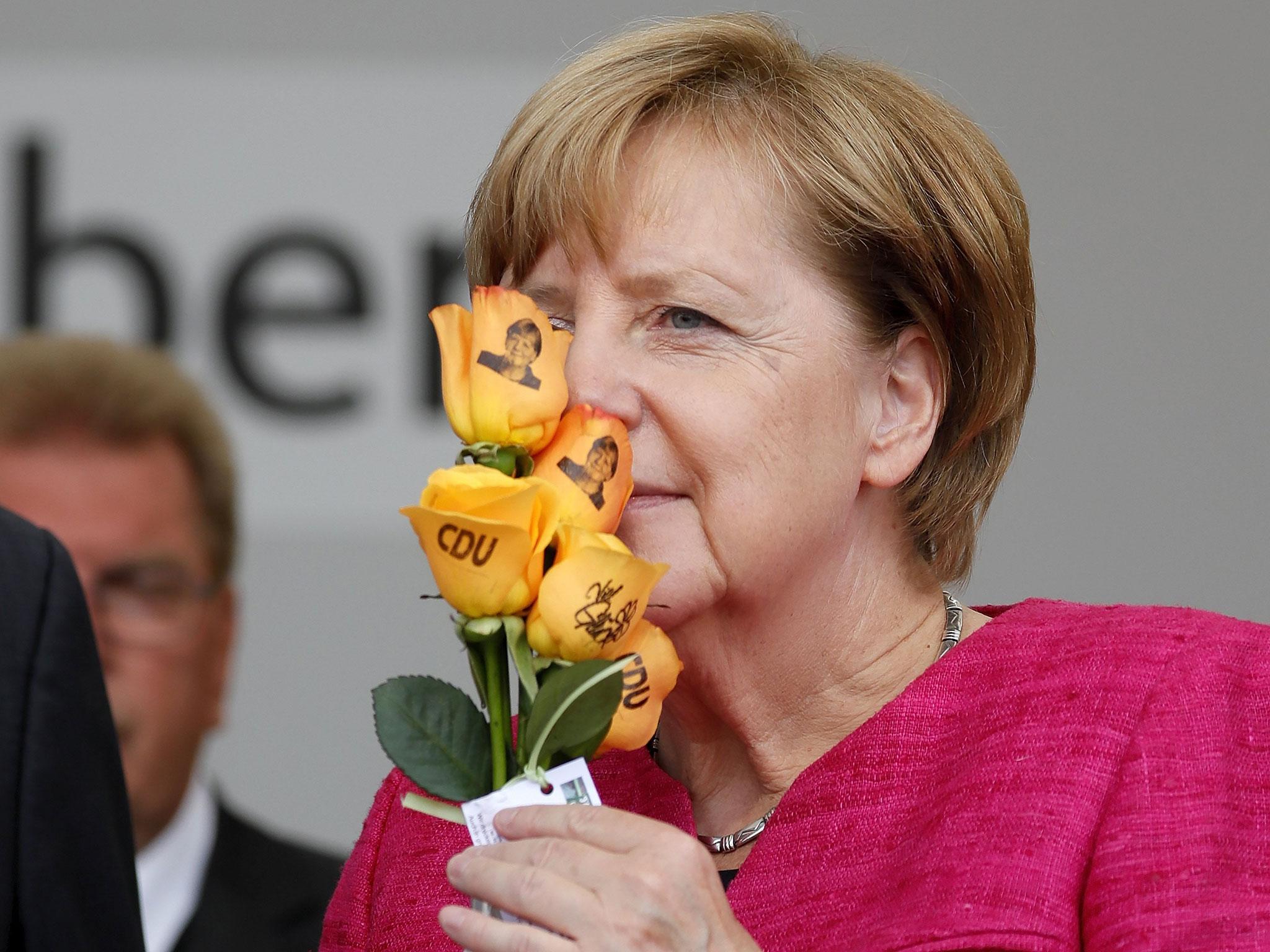 Angela Merkel smells some Christian Democratic Union (CDU) branded flowers at an election campaign event in Heppenheim