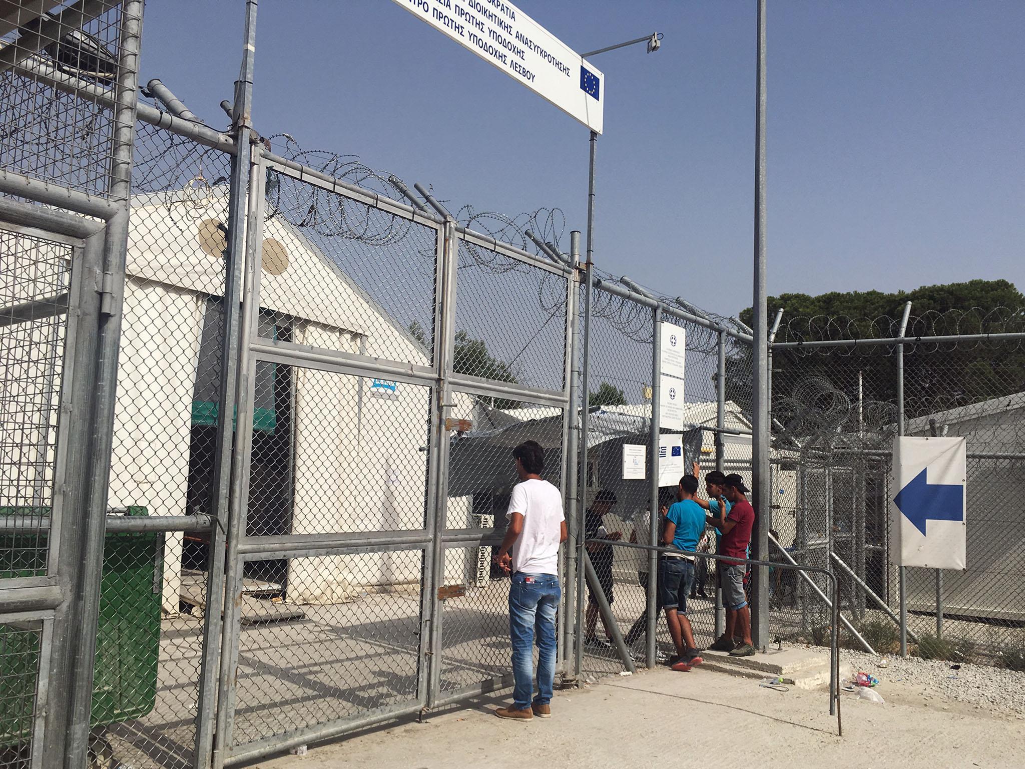 Refugees at the Moria camp wait outside the gates of the onsite detention camp, where others are being held