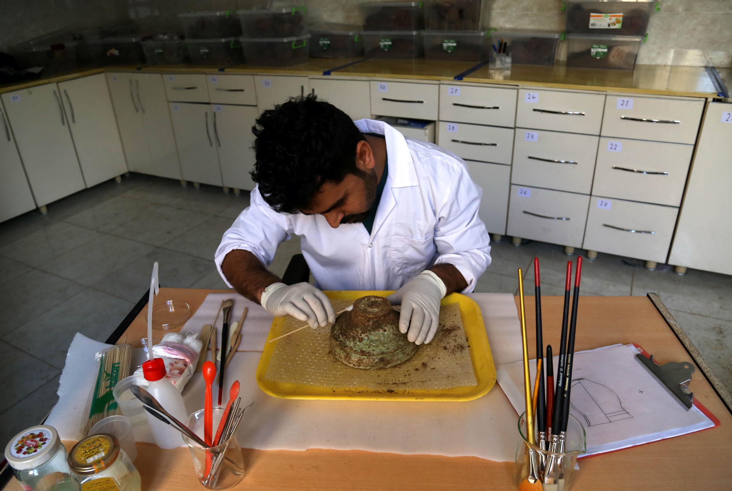 An archaeologist cleans an Assyrian bowl discovered in Iraqi Kurdistan.