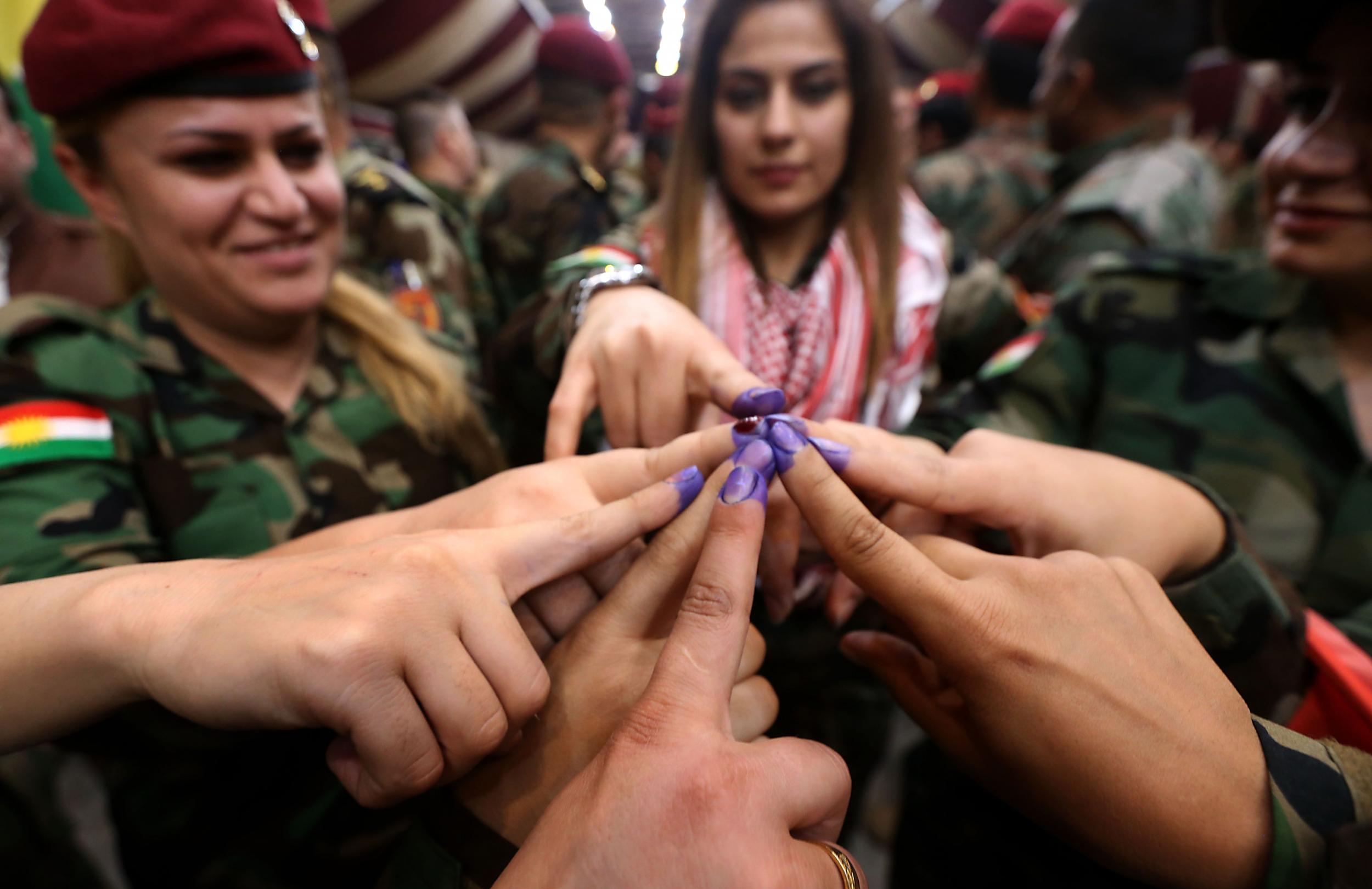 Members of a Kurdish Peshmerga battalion show their ink-stained fingers after casting their vote