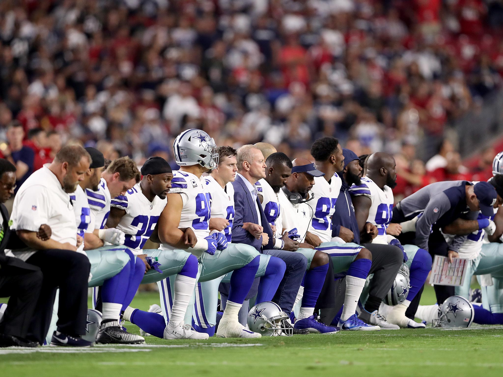 Members of the Dallas Cowboys link arms before the start of their NFL game against the Arizona Cardinals