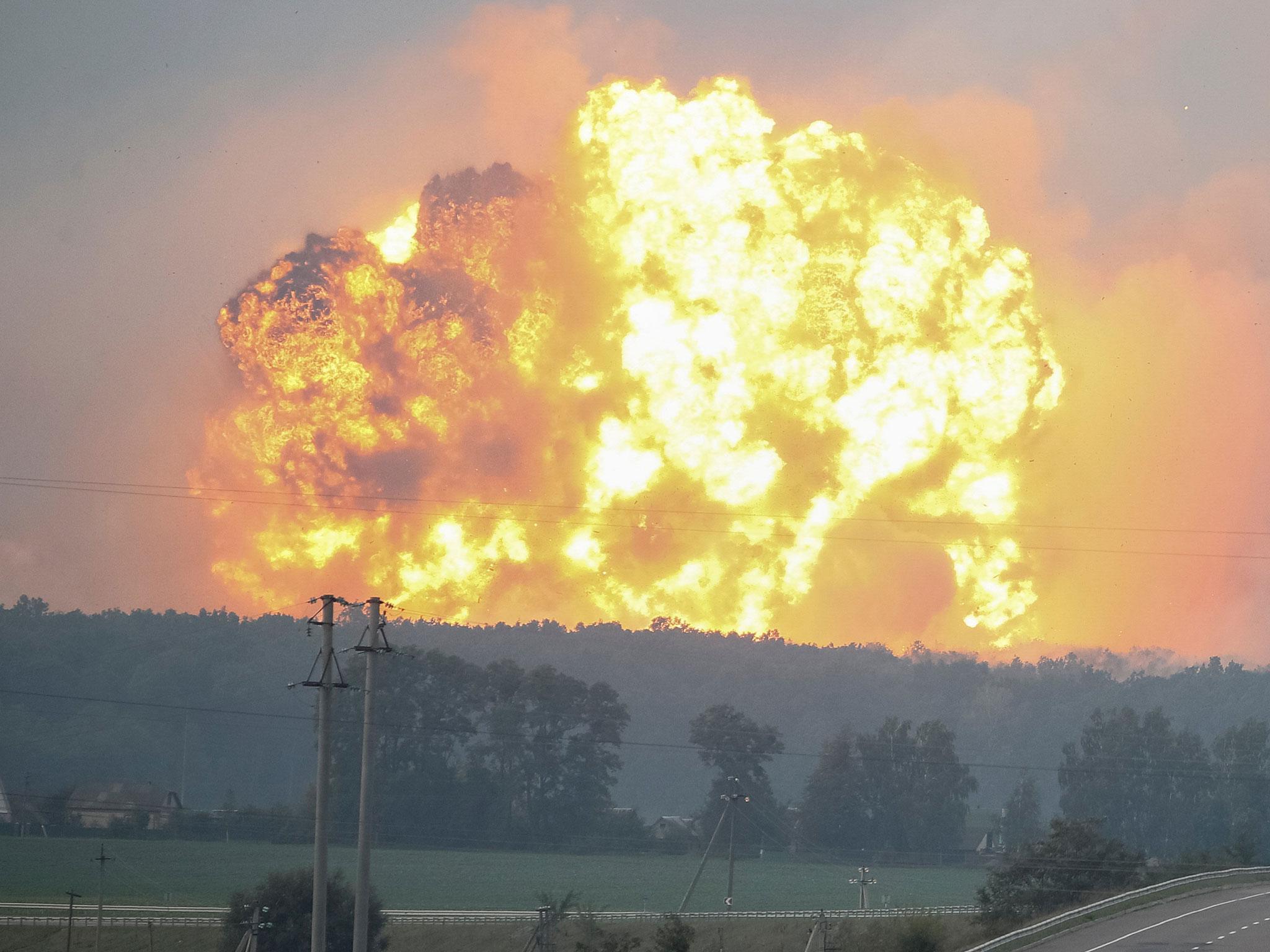 Smoke and flames rise over a warehouse storing ammunition for multiple rocket launcher systems