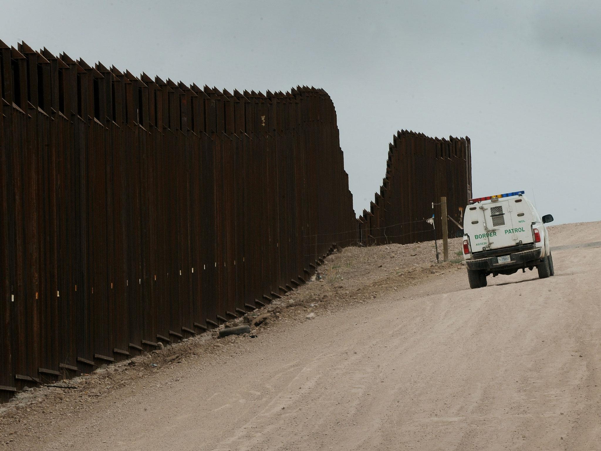 A US Border Patrol vehicle drives along the fence separating the US from Mexico