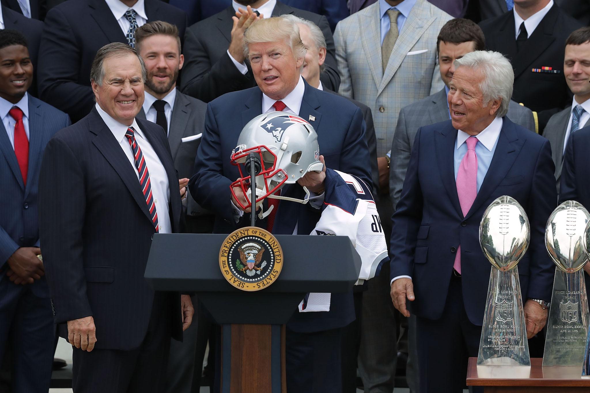 New England Patriots Head Coach Bill Belichick (L) and team owner Robert Kraft (R) present a football helmet to U.S. President Donald Trump