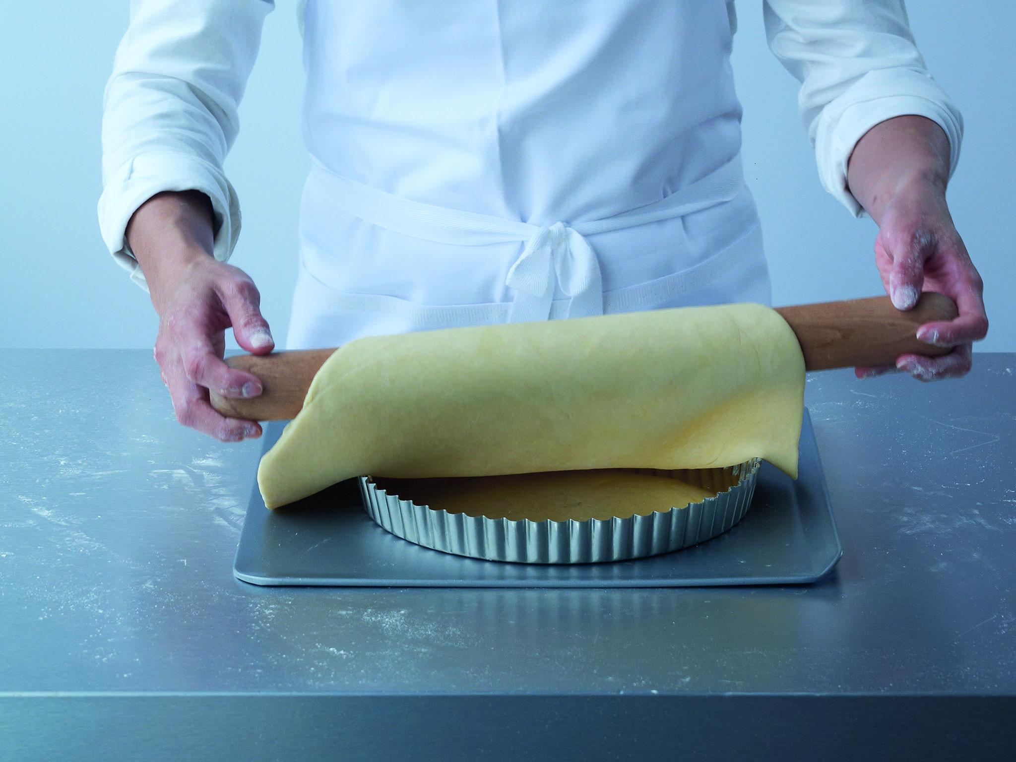 2. Carefully wrap the pastry once over the rolling pin to support it and place it over the flan tin or ring, set on a baking sheet, with the side of the pastry that was uppermost when rolling now against the baking sheet