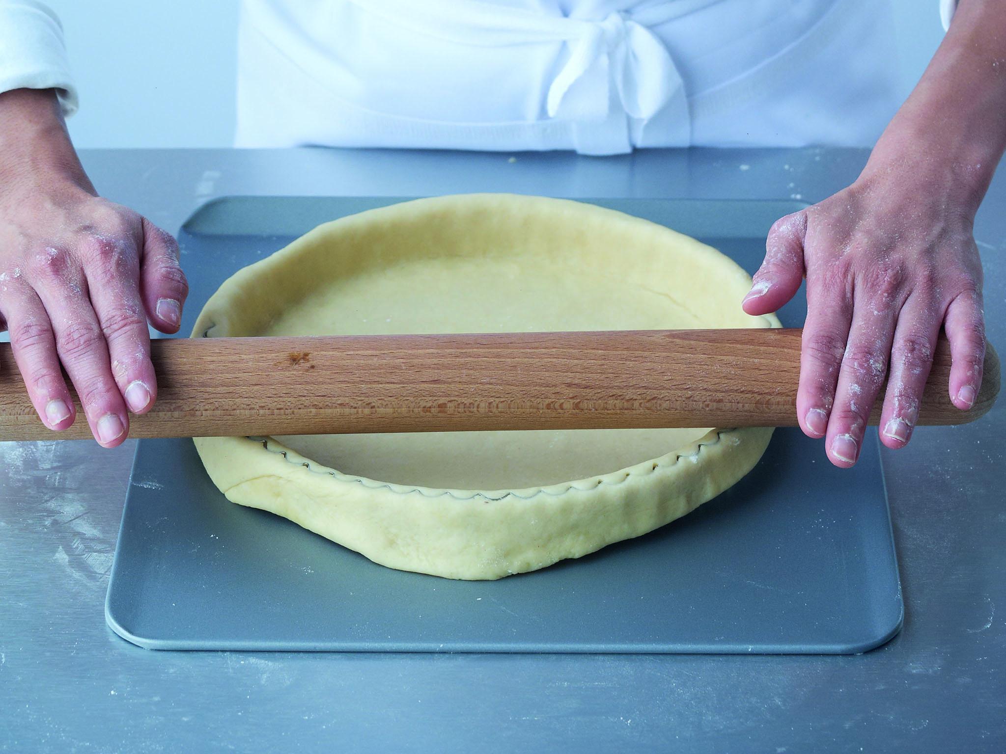 5. Using a rolling pin and starting from the middle of the flan tin or ring, roll away from you and cut through the pastry, removing the excess. Turn the baking sheet around and repeat