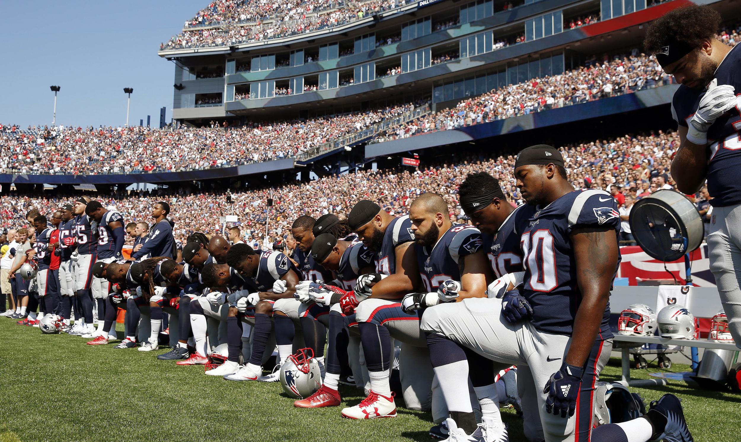 Several New England Patriots players kneel during the national anthem before an NFL football game