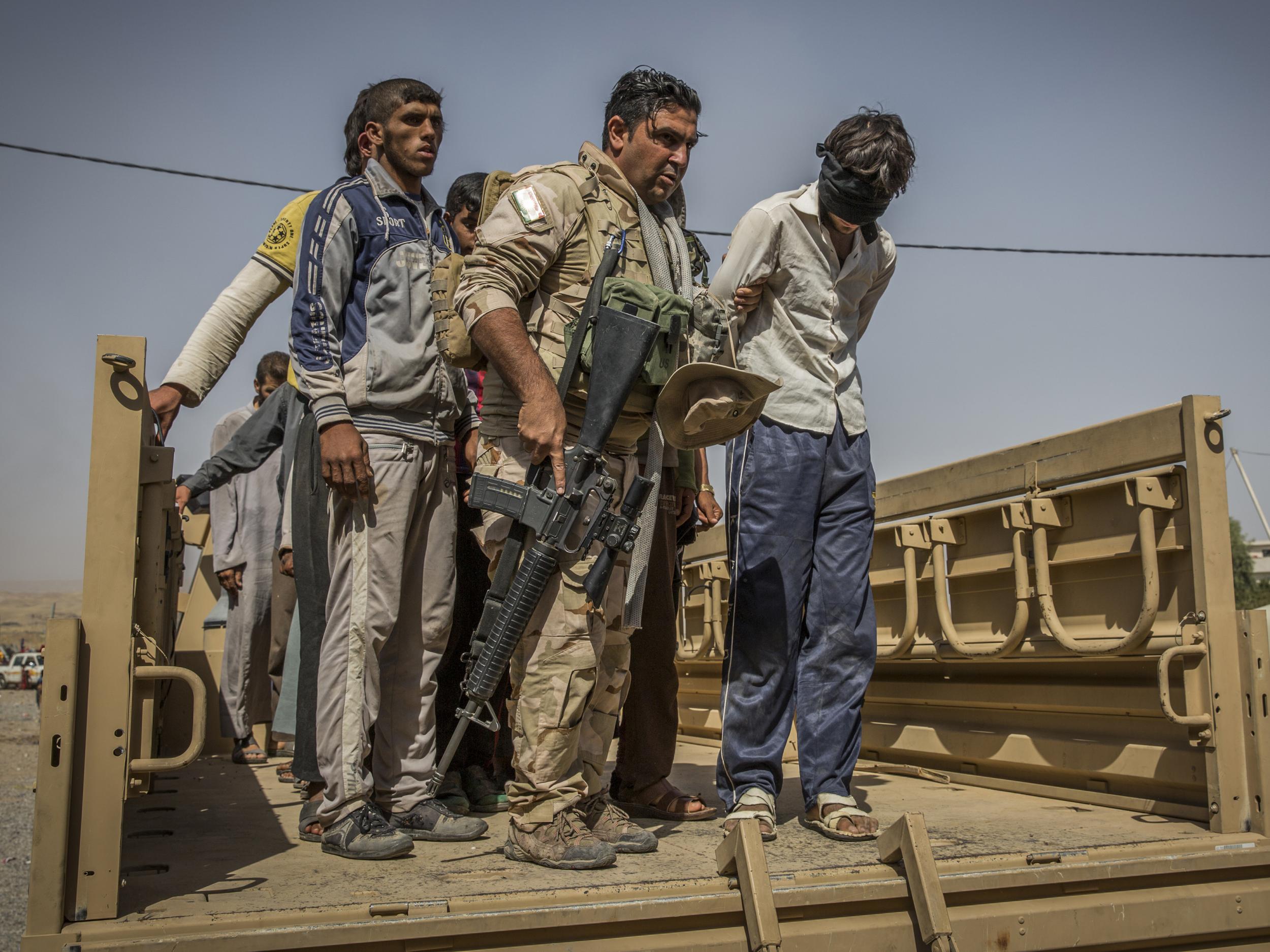 A Kurdish peshmerga soldier hands over a man suspected of being a member of Isis at a screening centre for displaced people near Kirkuk, Iraq, on 1 October 2017