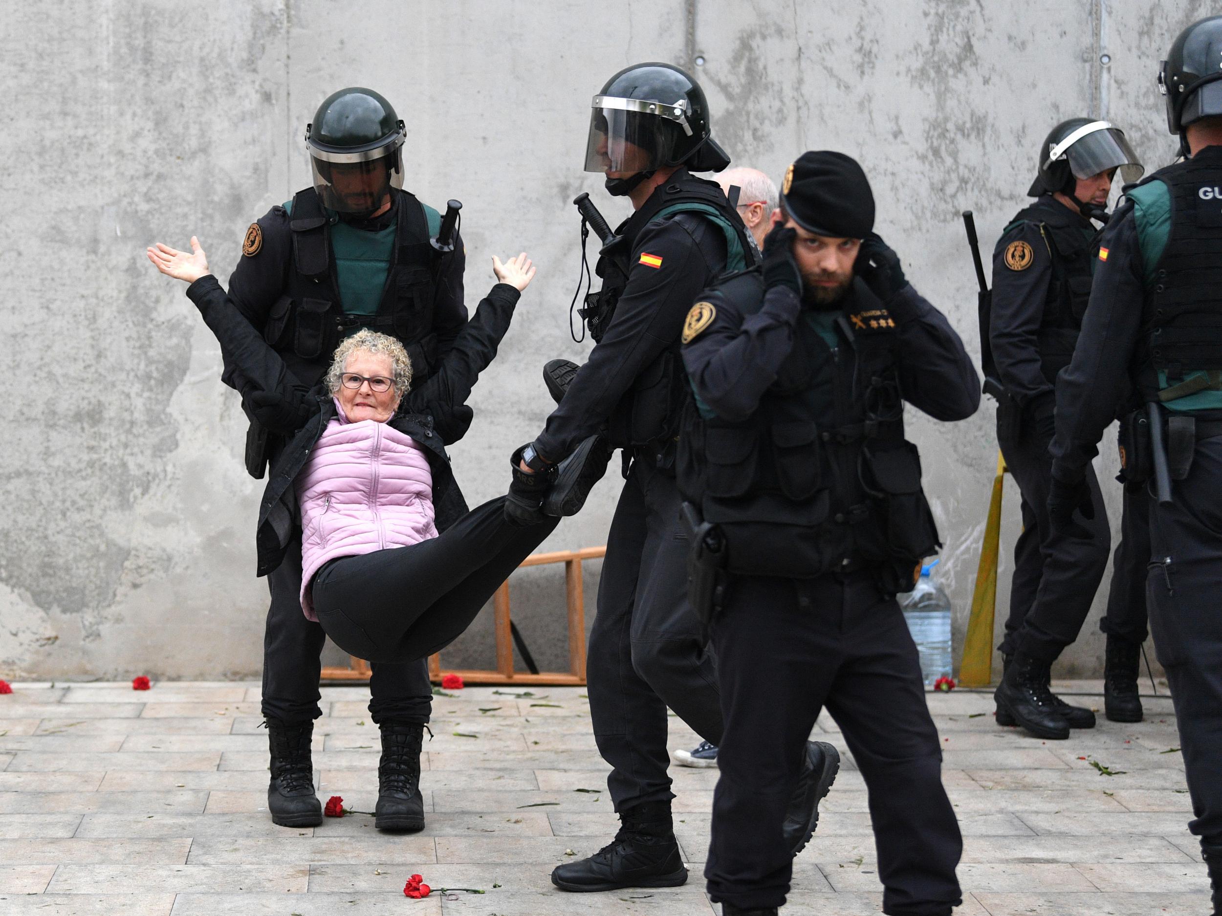 Police carry away an elderly woman after she tried to vote at a polling station in Catalonia