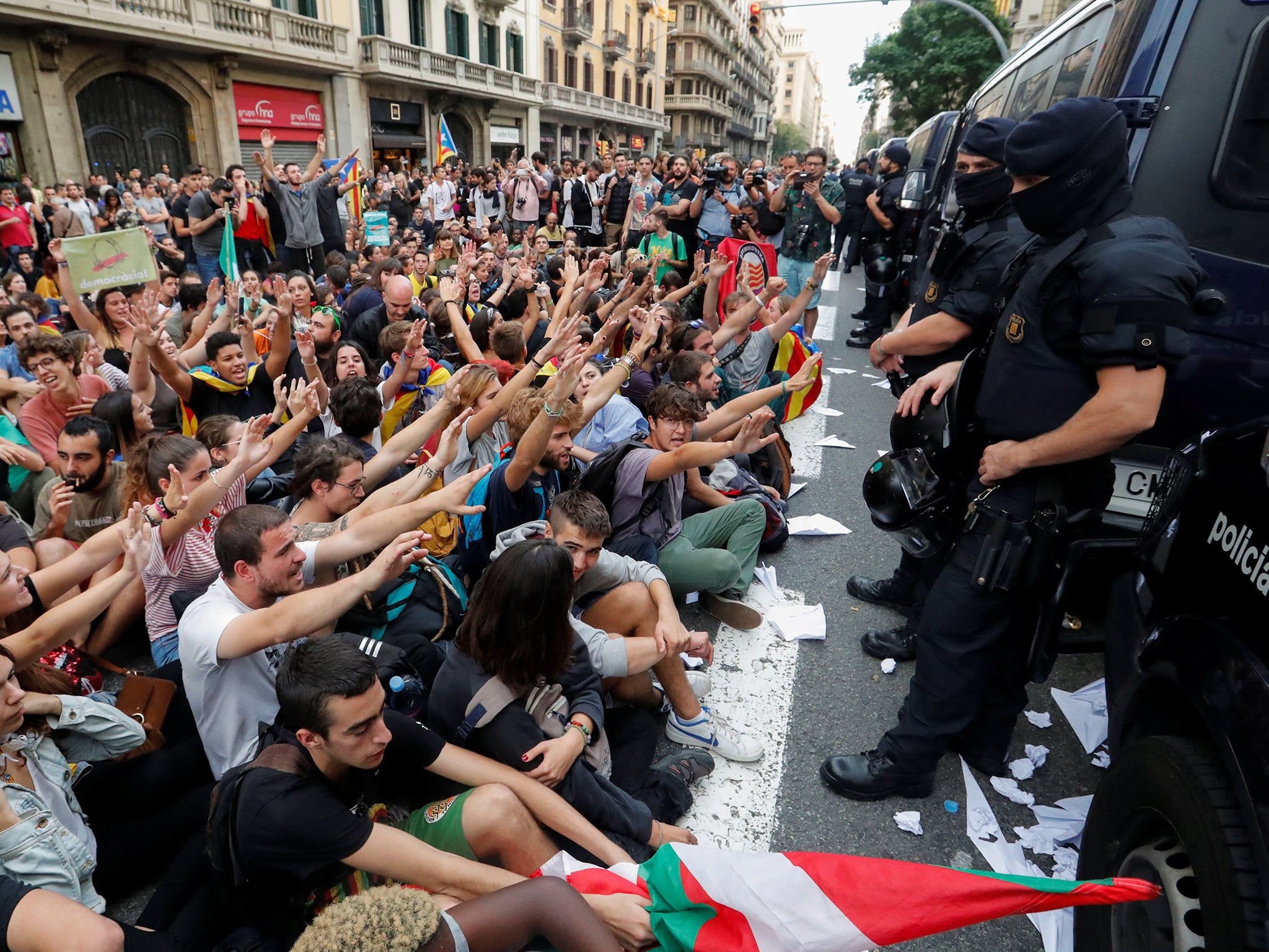 People shout slogans during a protest as Catalan regional police officers stand guard outside National Police station, in Barcelona