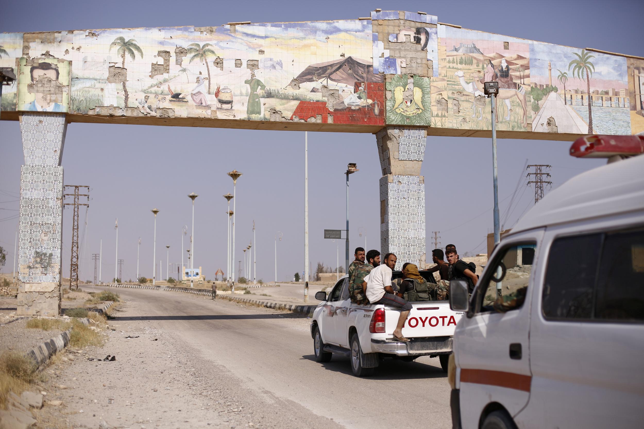 Syrian army soldiers ride on the back of a truck in al-Bugilia, north of Deir Ezzor, on 21 September 2017