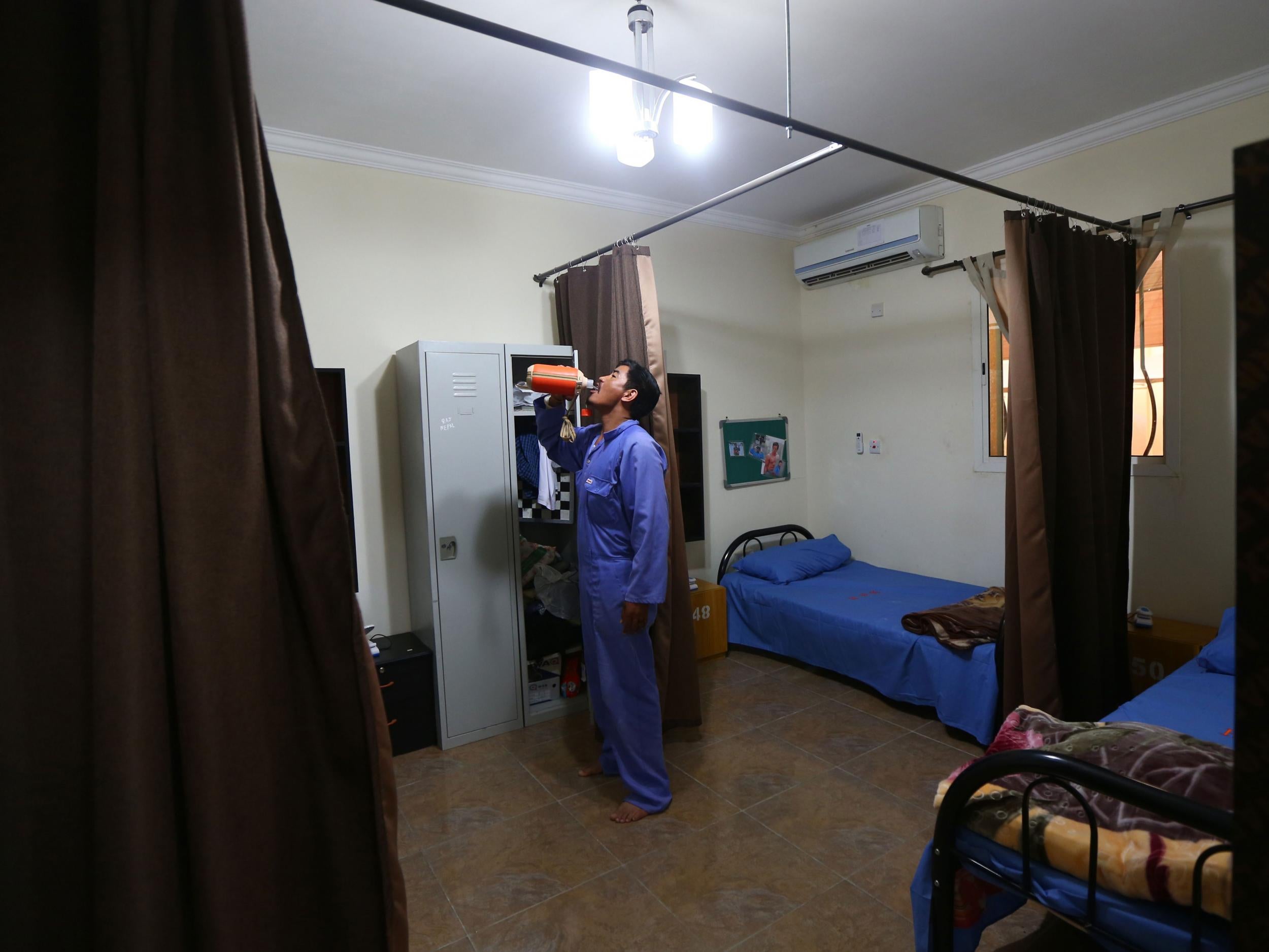 A migrant worker gets ready for bed in his sleeping quarters