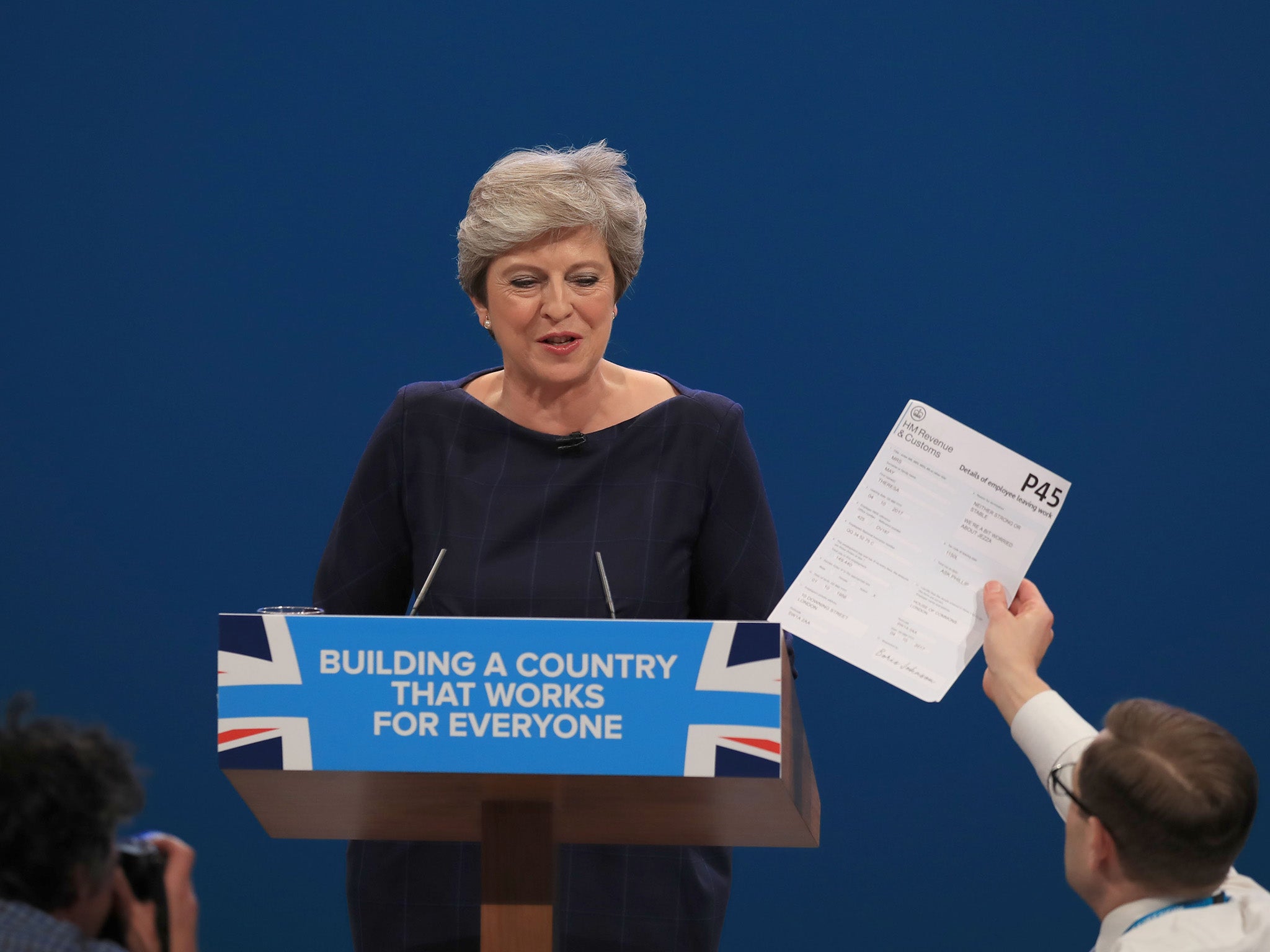 Comedian Simon Brodkin, also known as Lee Nelson hands the Prime Minister a mock P45 during her keynote speech (PA)