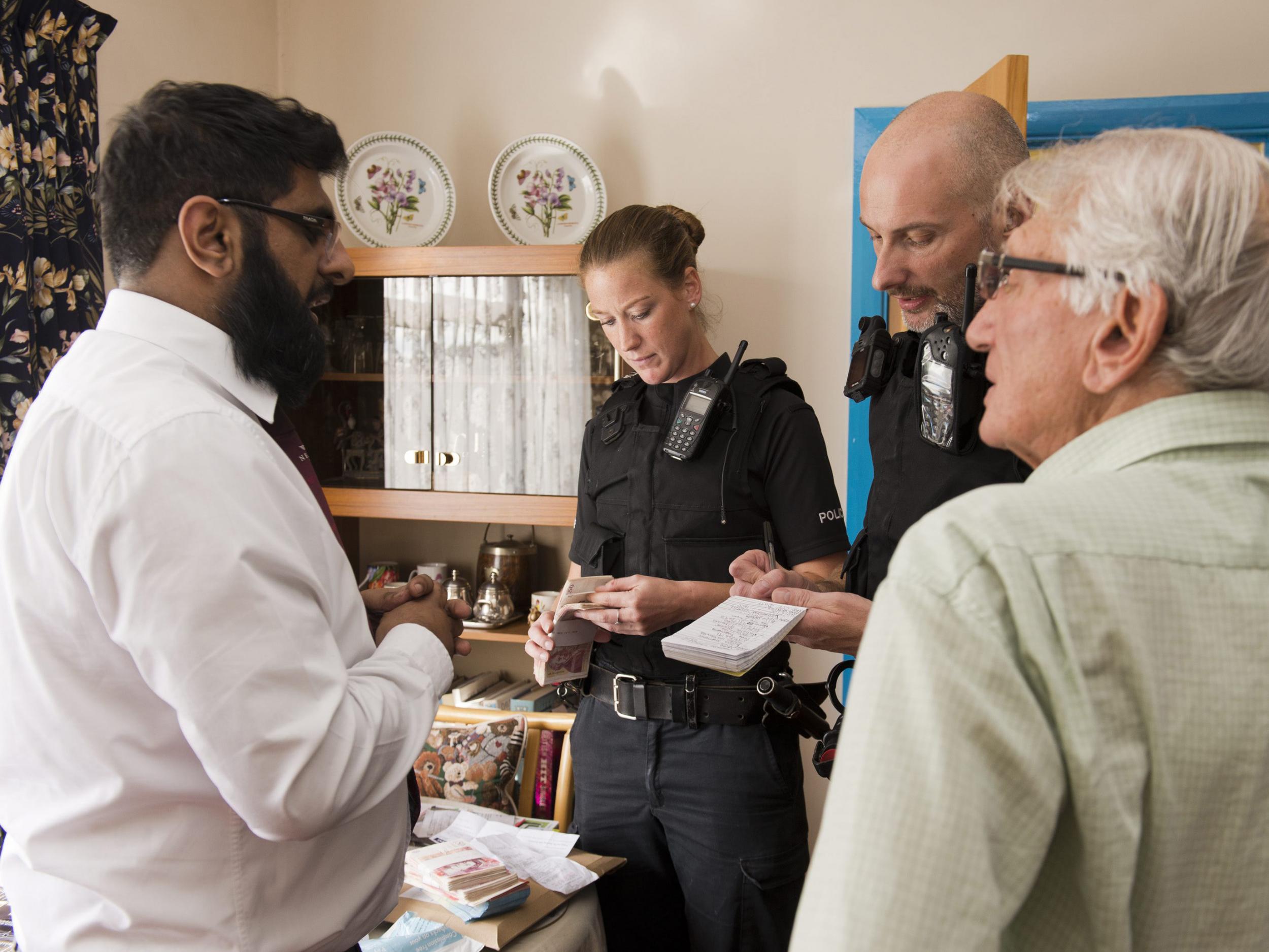 Izy Rashid (left) talks to the police while an officer checks the money he had just handed back to Mr Stone