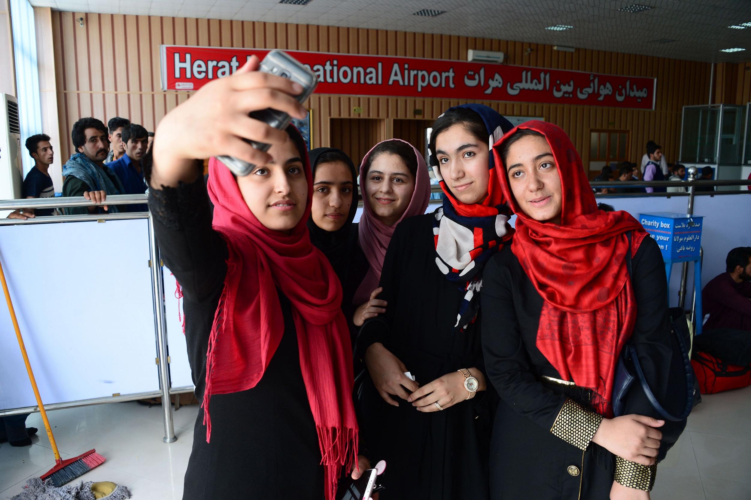 Afghan teenagers from the Afghanistan Robotic House initiative take pictures at Herat International Airport before travelling to the US for a competition