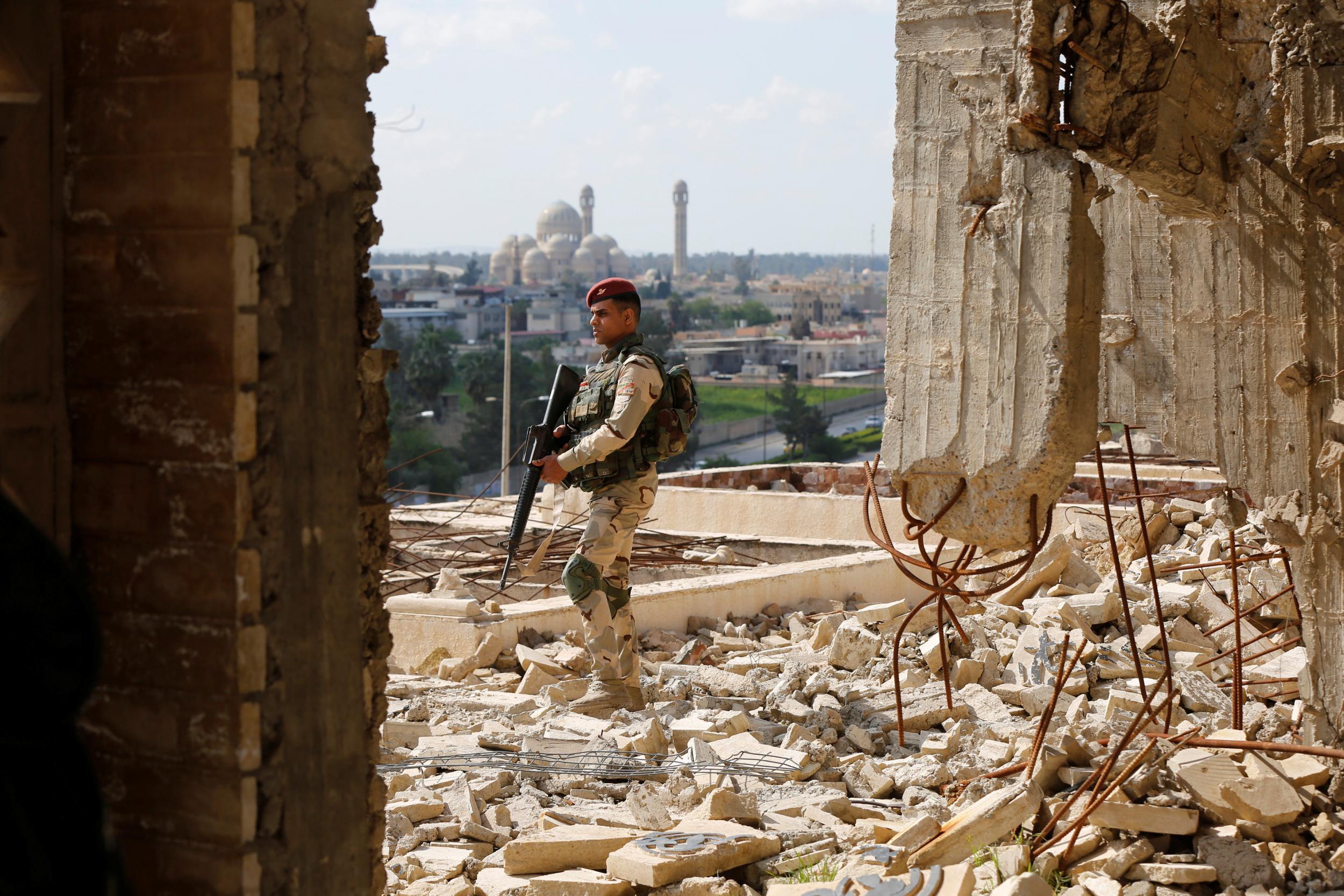 A member of the US-backed Iraqi security forces stands guard at a shrine destroyed by air strikes in east Mosul, Iraq, on 19 April 2017