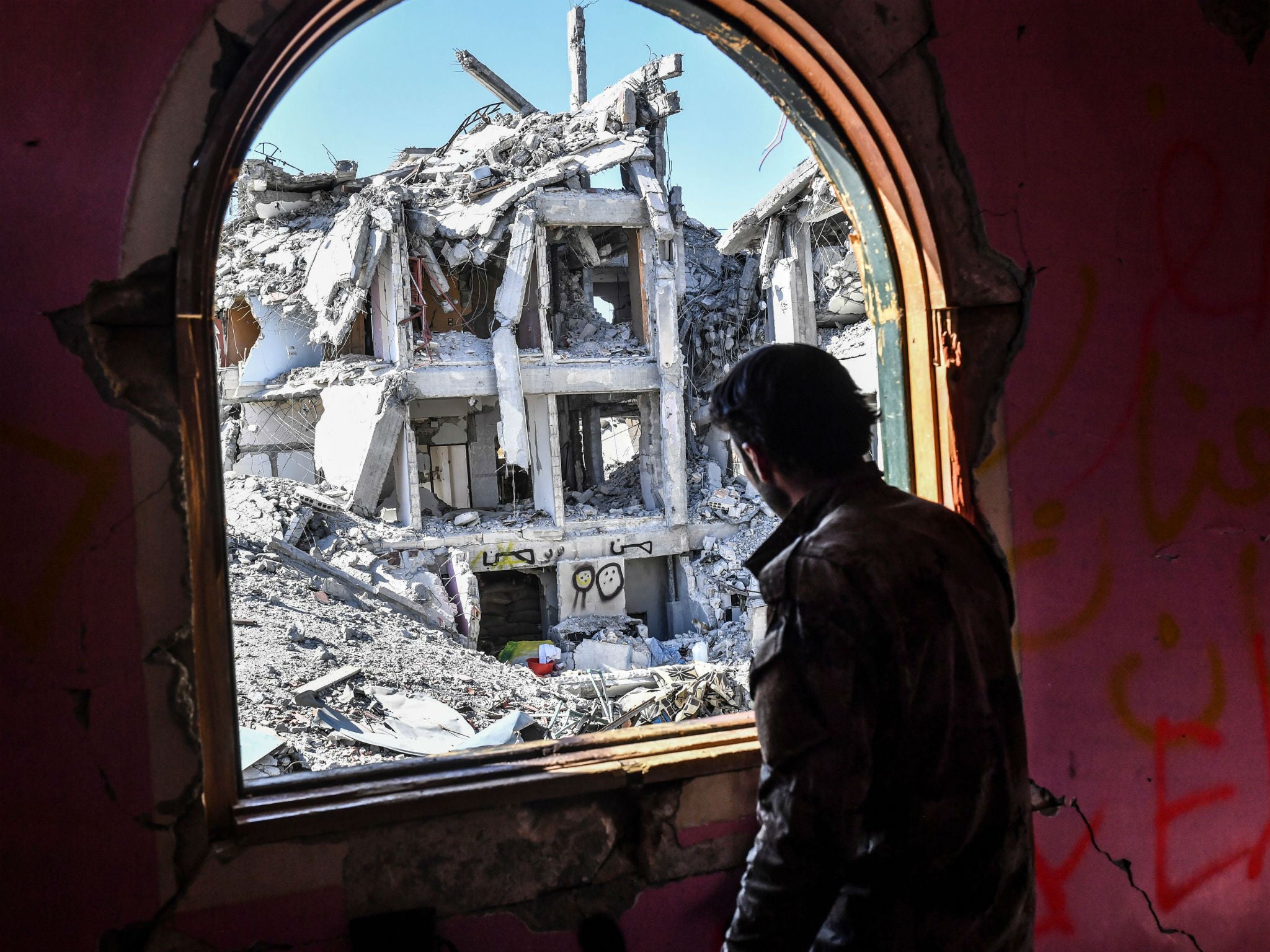 A member of the Syrian Democratic Forces (SDF), backed by US special forces, looks out from a building at the frontline in Raqa