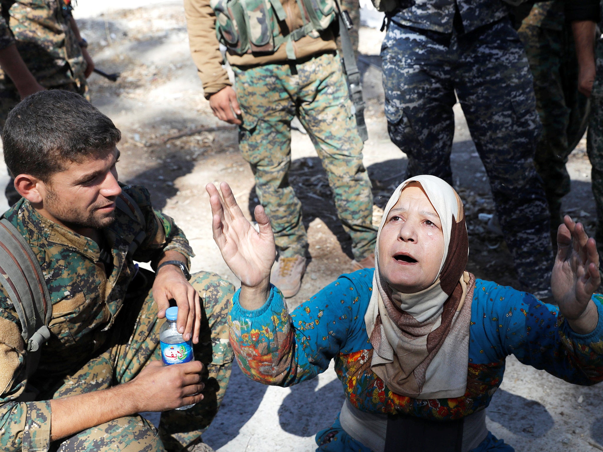 A civilian prays after she was rescued by SDF fighters from the city’s stadium during the battle for the city (Reuters)