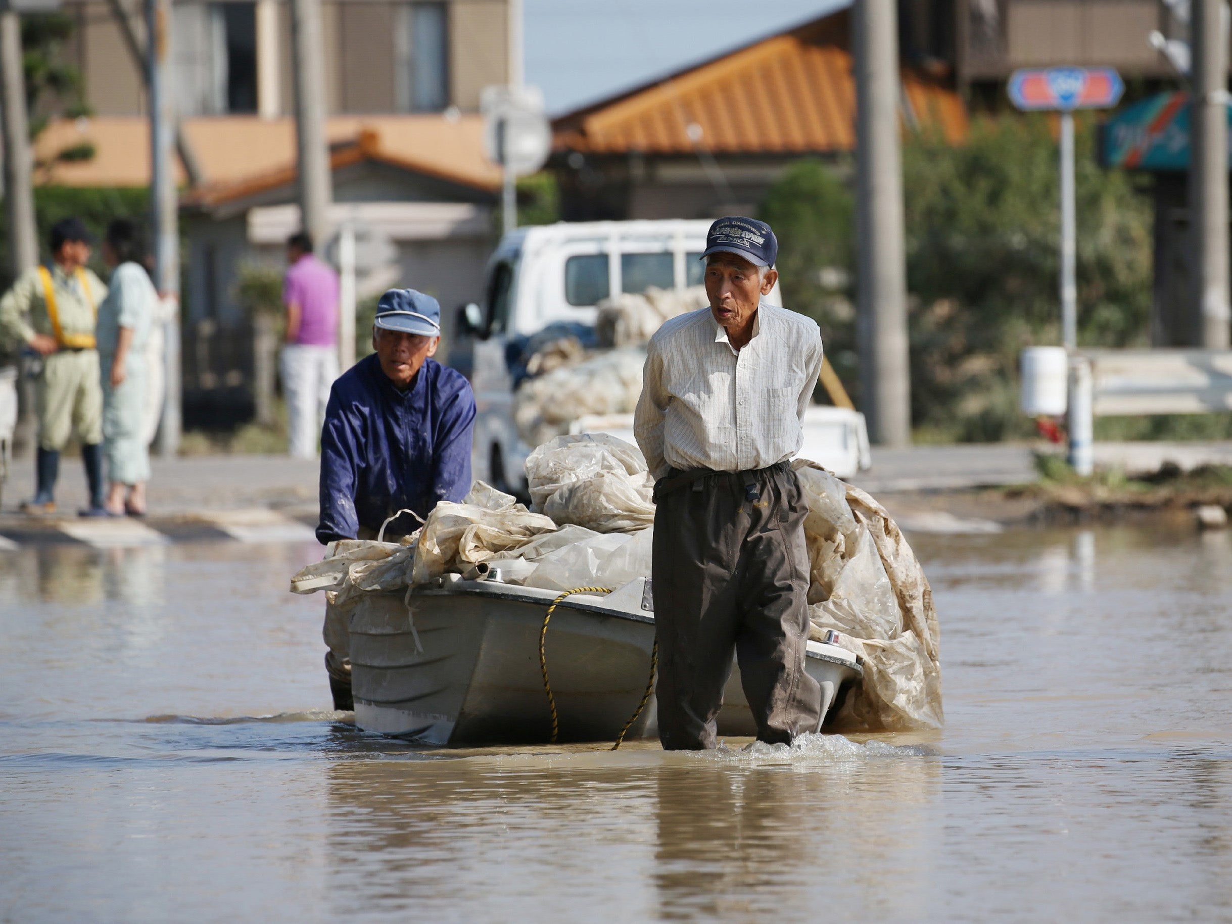 Local residents Noshimasa Yoshida (right) and Ei Hirose carry their agriculture materials with a boat at Joso in Ibaraki prefecture on 15 September, 2015