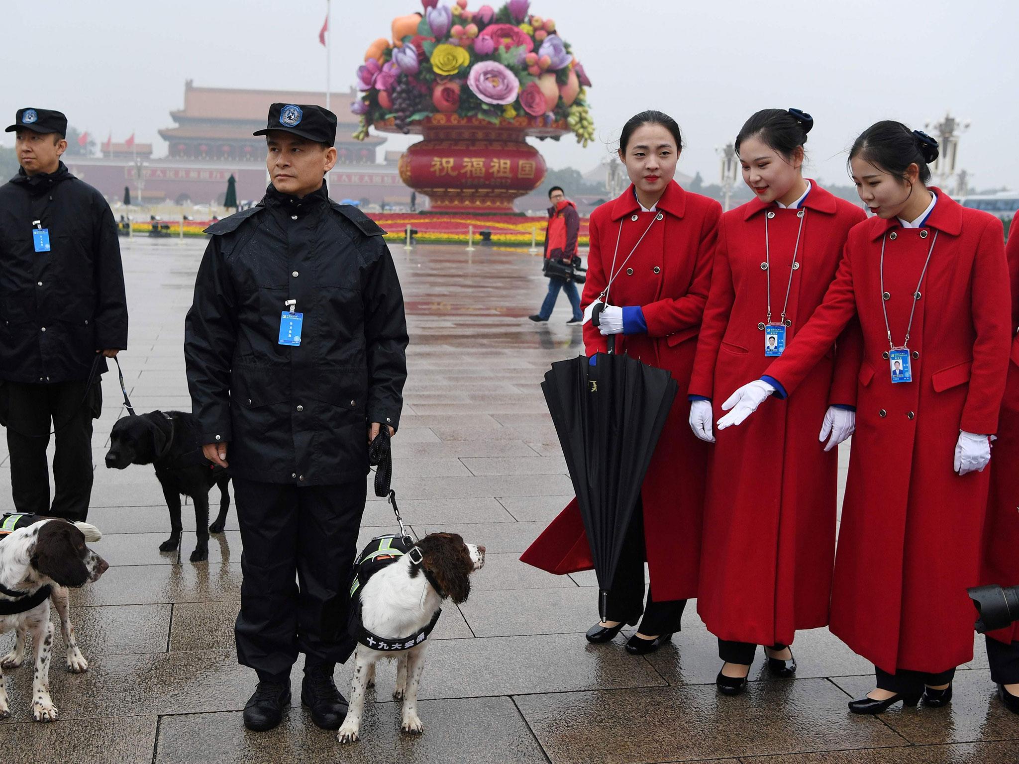 Attendants look at sniffer dogs while posing for photos in Tiananmen Square during the opening ceremony of the 19th Communist Party Congress in Beijing