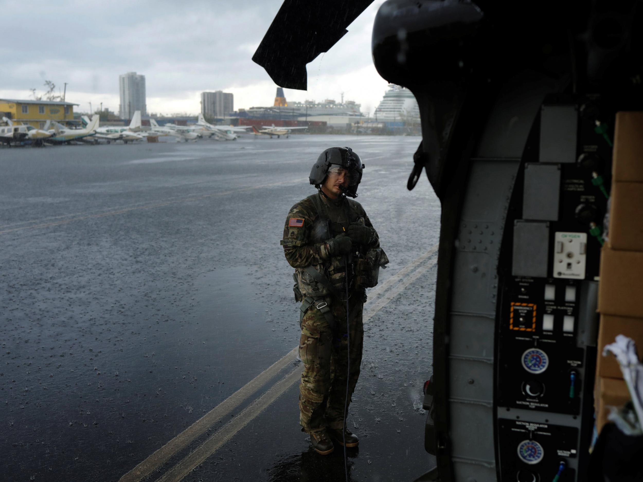 Crew chief Kenney shelters under the blade of an HH-60 Blackhawk helicopter from 101st Airborne Division's "Dustoff" unit preparing to take off during recovery efforts following Hurricane Maria, in Isla Grande, Puerto Rico, October 6, 2017