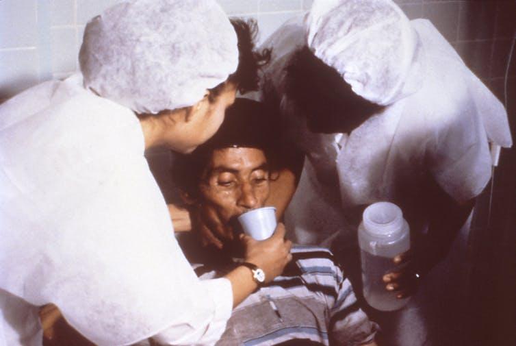 A patient drinks a rehydration solution in order to counteract cholera-induced dehydration, 1992