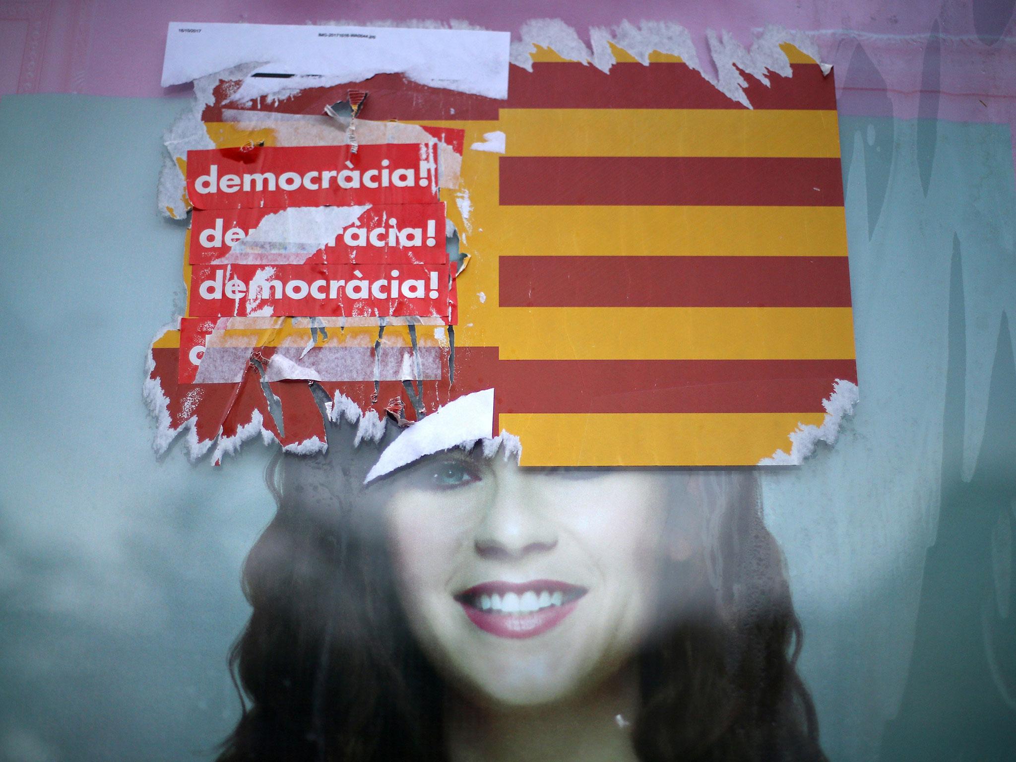 Stickers reading 'Democracy!' are seen on Spanish and Catalan flags during protests against the transfer of bank headquarters out of Barcelona