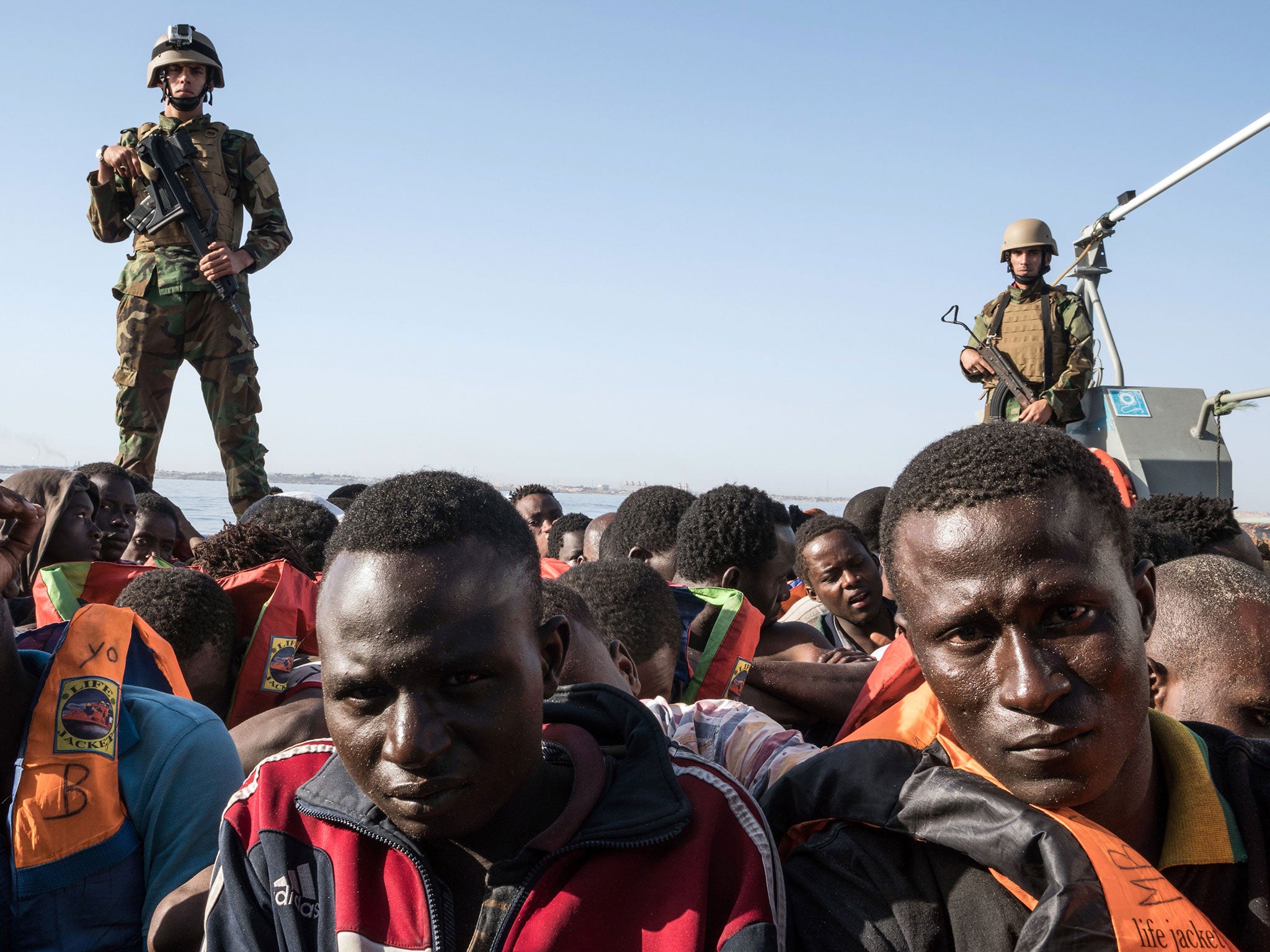 Members of the Libyan coastguard stand on a boat while detaining 147 migrants attempting to reach Europe off the coastal town of Zawiyah on 27 June 2017